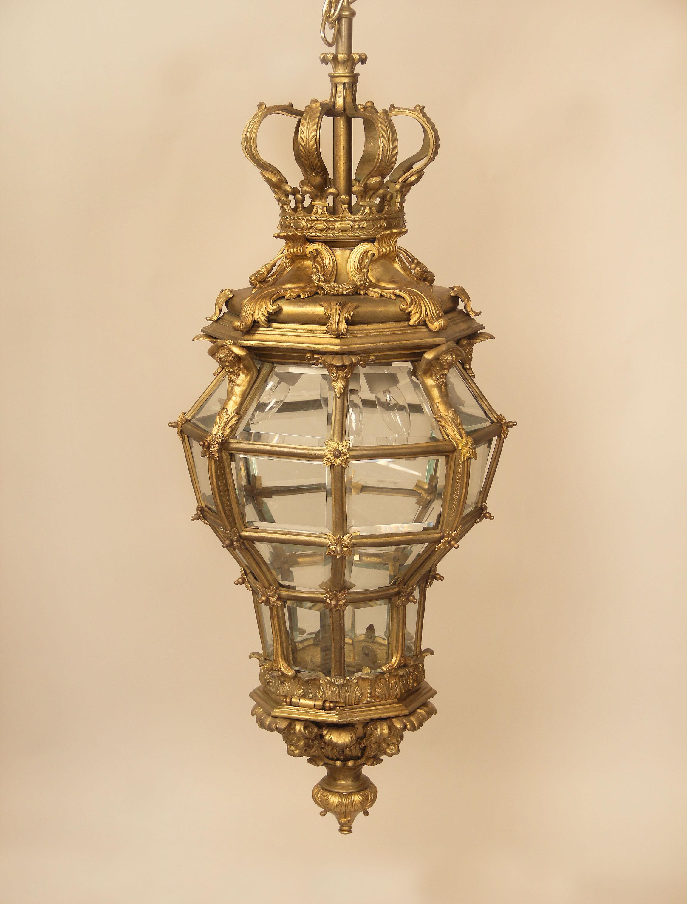 A fantastic late 19th century gilt bronze and glass 'Versailles' hall lantern.

After the Versailles model, of octagonal and cage form, with a corona finial above four Neptune figures and seashells, the base with lion masks. Four interior lights.