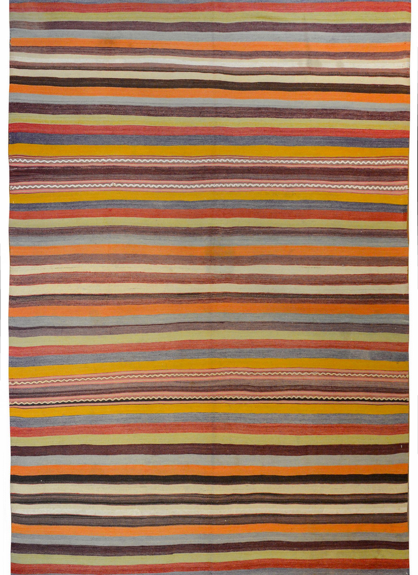 A fantastic mid-20th century Turkish Kilim rug with a beautiful multicolored stripe pattern containing orange, gold, green, indigo, cream, and black vegetable dyed wool.