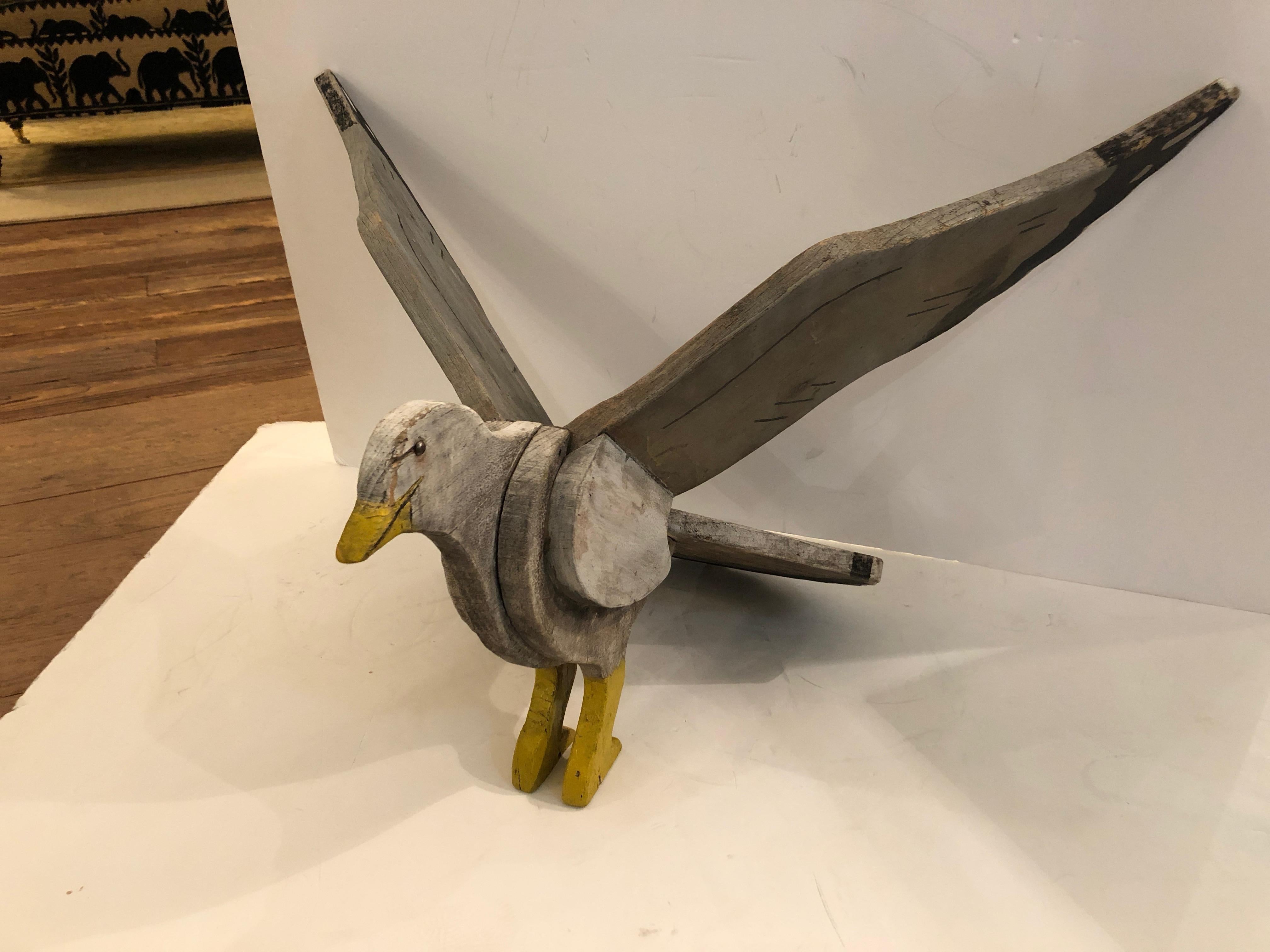 A wonderful Folk Art carved and hand painted wooden seagull on base having an authentic weathered patina and faded grey, black and yellow color palette.