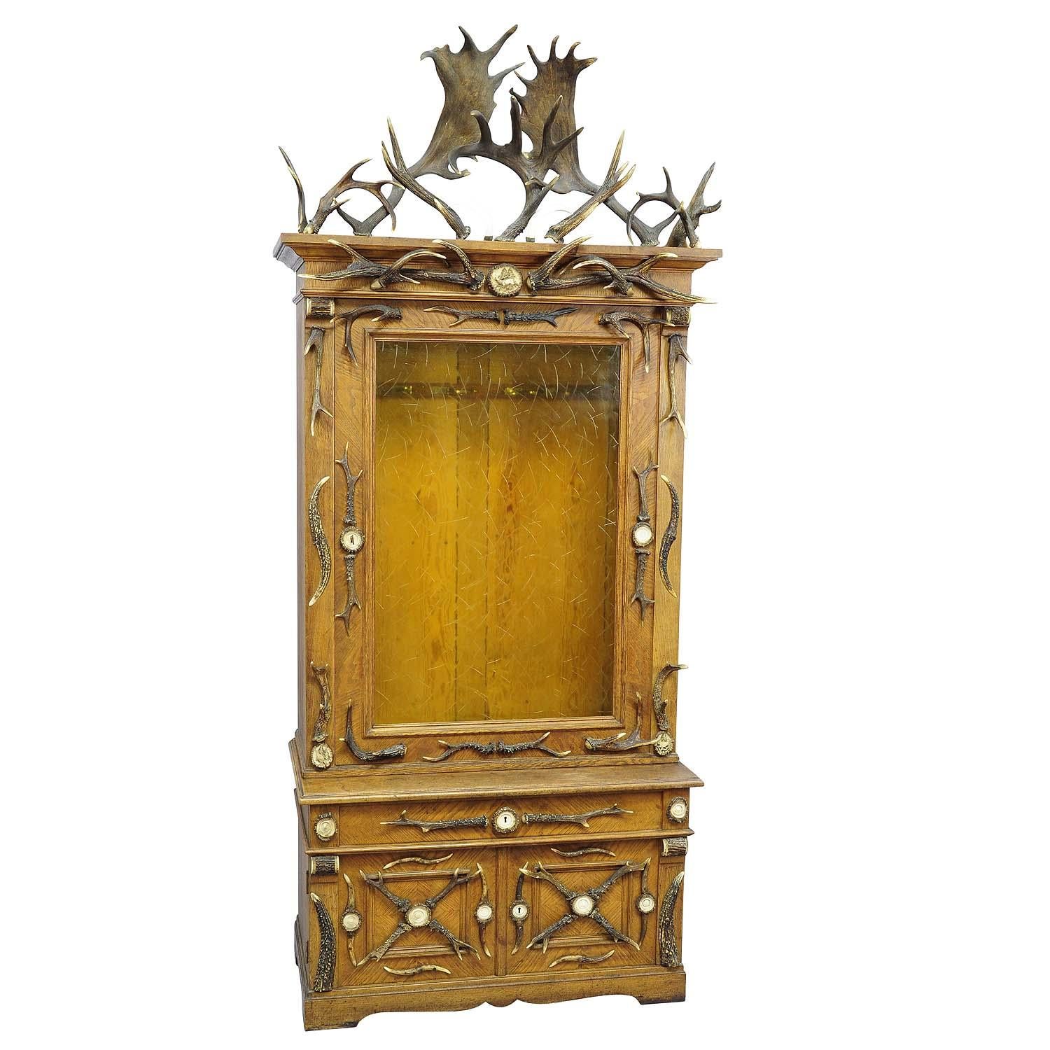Fantastic oak wood gun cabinet with horn decoration ca. 1900

An antique Black Forest oak wood cabinet. Richly decorated with several antlers from the stag and fallow deer, wild boar tusks, turned horn ends and figural handcarved horn roses. Front