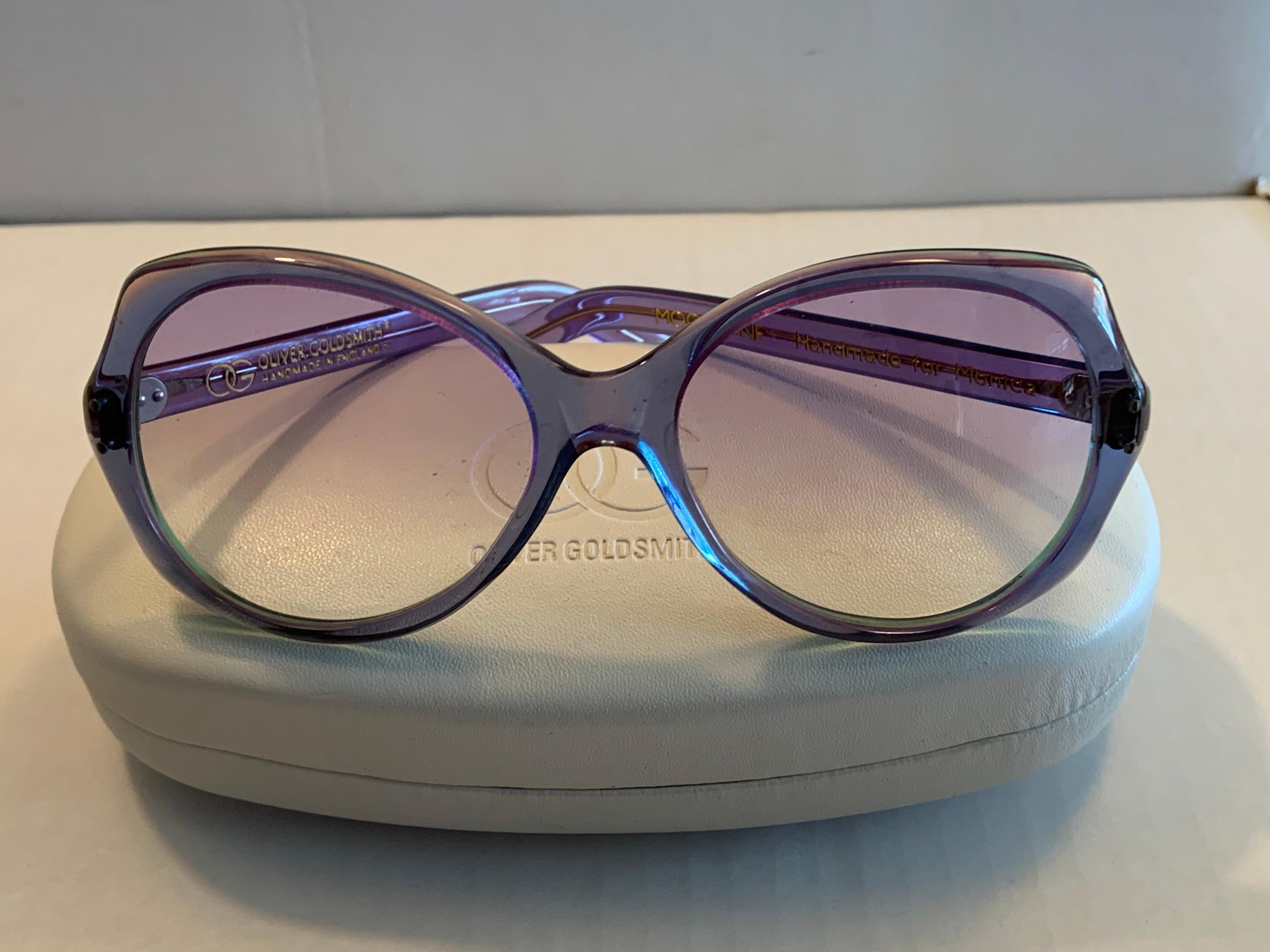 Oliver Goldsmith designed these hand made sunglasses with lavender tinted lenses paired with lavender, green and magenta layered frames to create a truly eye catching look! The sunglasses are in pristine condition and appear to be unworn. They are