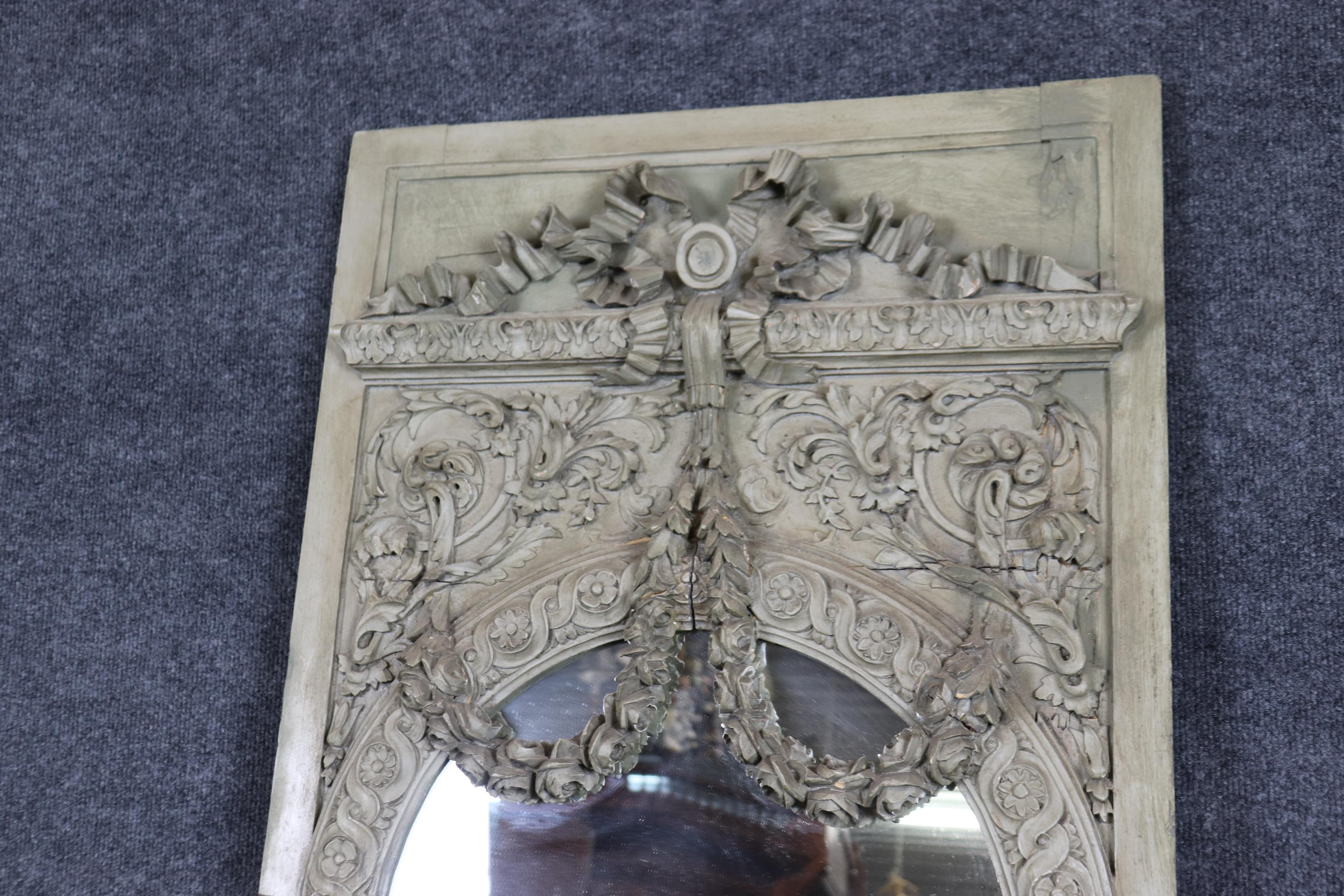 This is a sleeper...Don't miss this one. This absolutely gorgeous French trumeau mirror has its original gray painted finish and incredible carving, with age splits in the seams and incredible patina and naturalistic flowers in the garlands. The