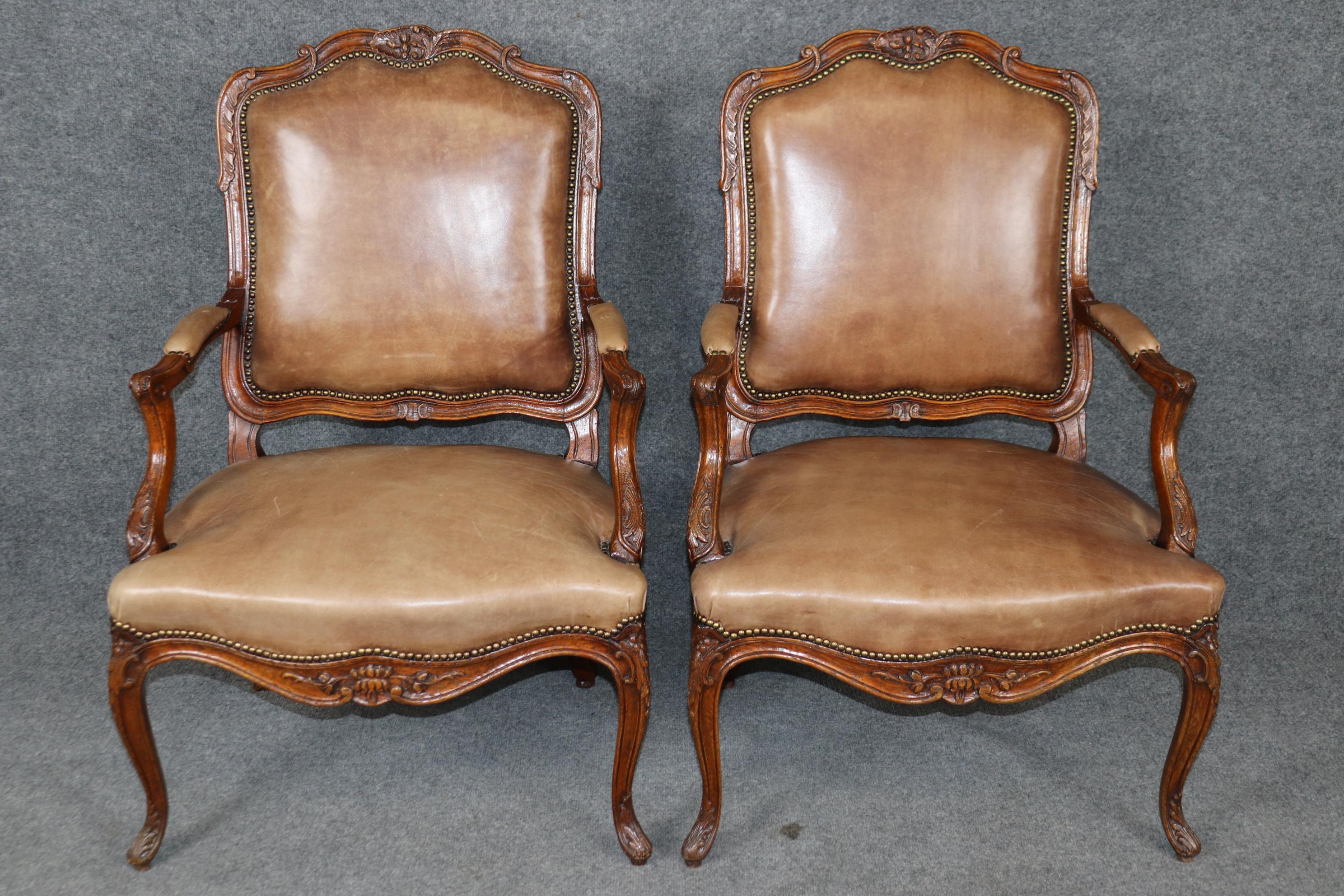 Si tratta di una coppia di poltrone in pelle Luigi XV di manifattura francese con splendide cornici in quercia intagliata e decorazioni in ottone brillante. Le sedie sono in buone condizioni d'epoca e la pelle, rivestita più di recente, è in buone