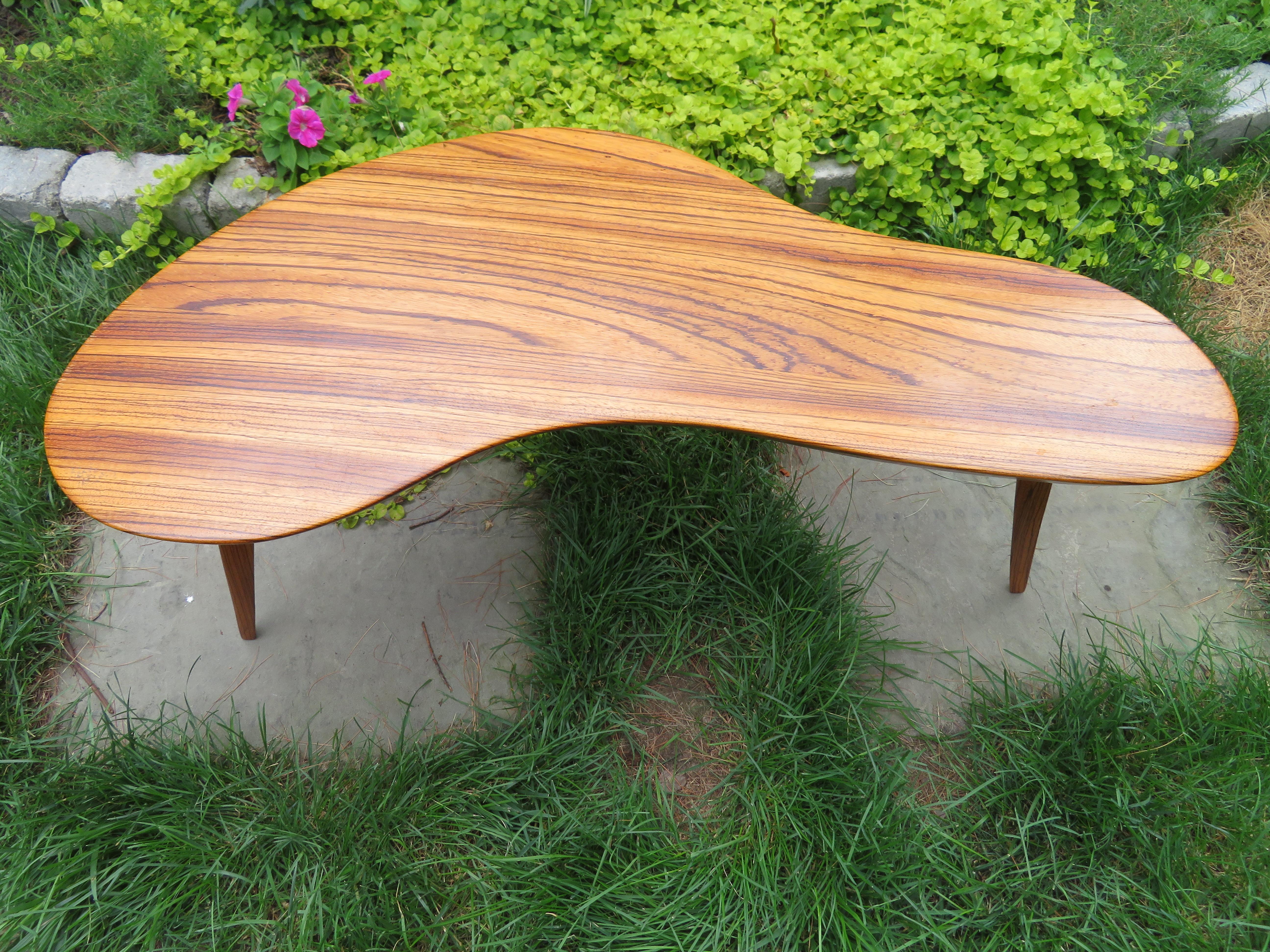 Beautiful petite handcrafted boomerang shaped coffee table made from solid zebrawood. Striking grain throughout and beautifully shown with beveled edge and three solid triangular wood legs. Table has makers mark branded to underside 