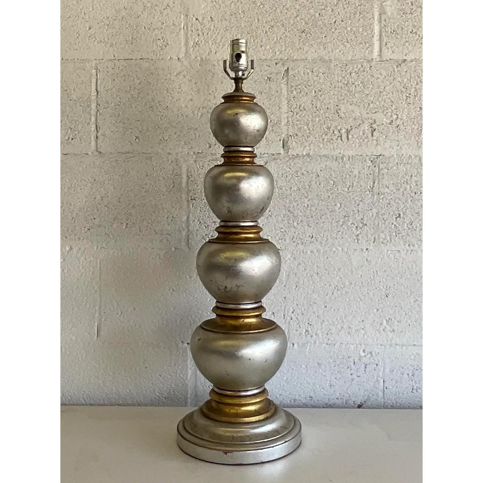 Stunning vintage Regency table lamp. Beautiful turned wood lamp with a brilliant silver leaf and gilt finish. Done in the manner of James Mont. Large and impressive. Acquired from a Palm Beach estate.
