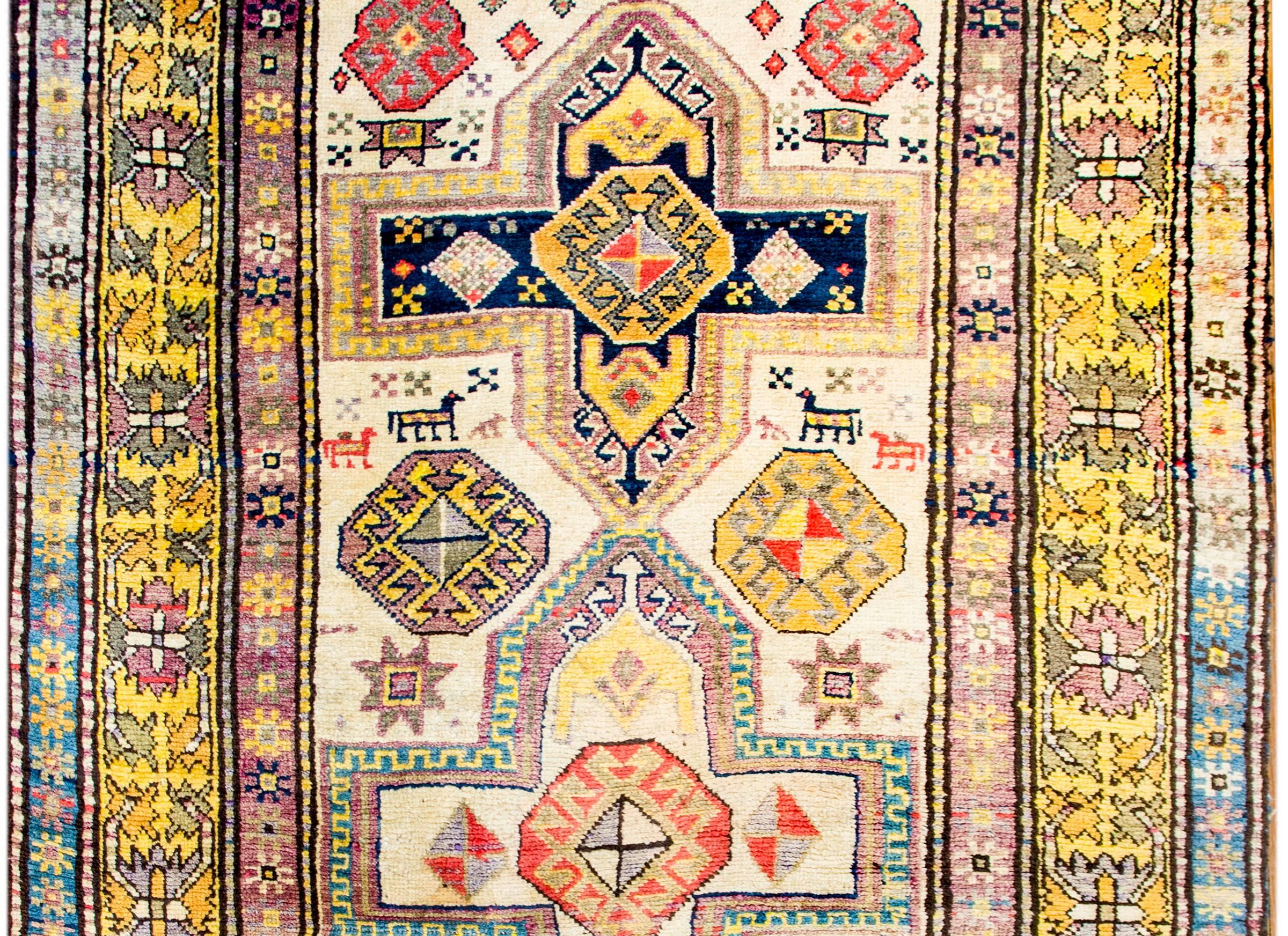 A fantastic vintage Turkish Konya rug a beautiful tribally woven pattern with multiple cross-form and stylized floral medallions amidst a field of goats, all woven in crimson, gold, orange, indigo, green and white vegetable dyed wool, on a white