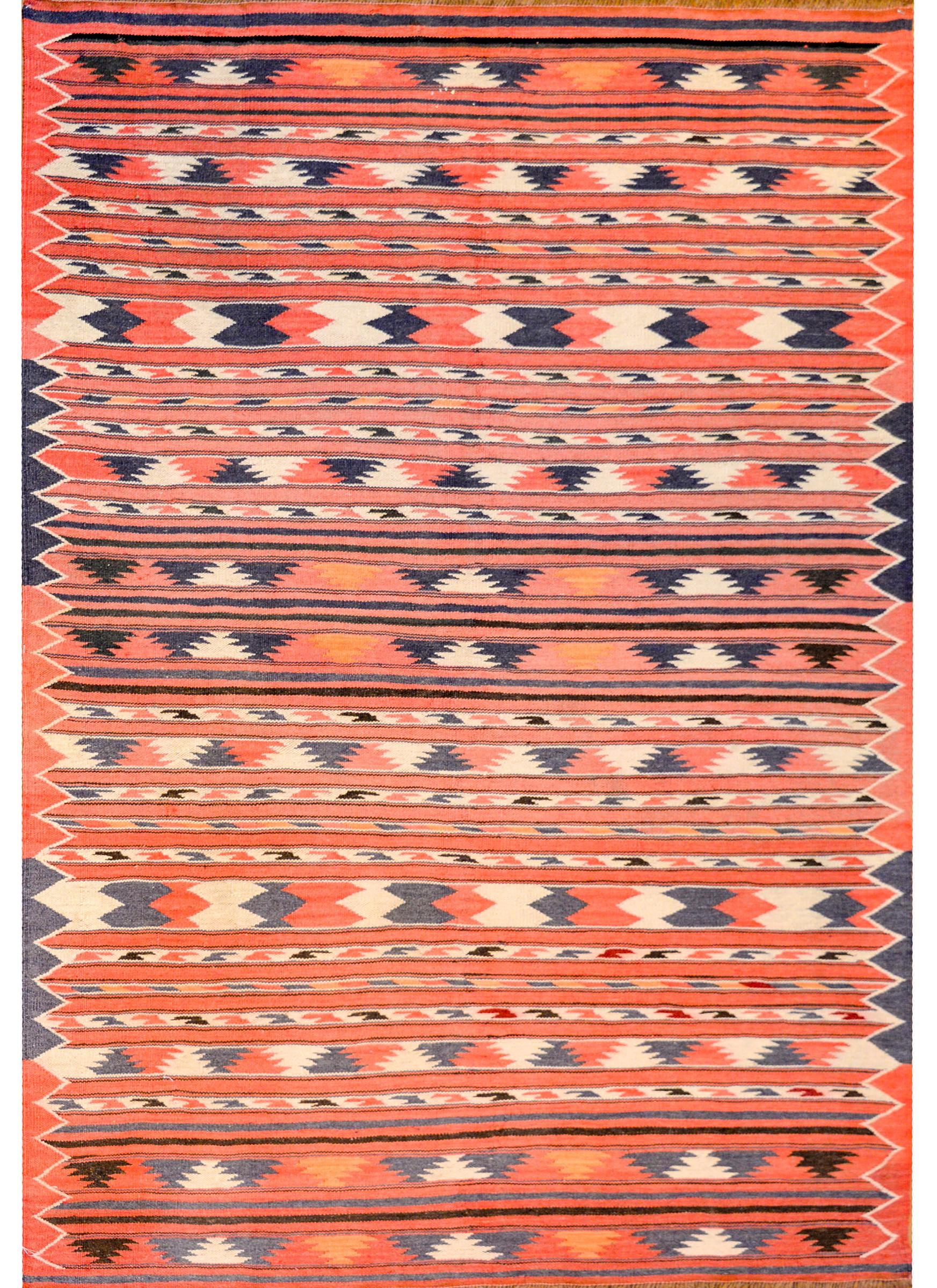 A fantastic mid-20th century Persian Turkmen rug with an all-over striped pattern woven in crimson, indigo, black, orange, and white, vegetable dyed wool, surrounded by a matching border of similar design.