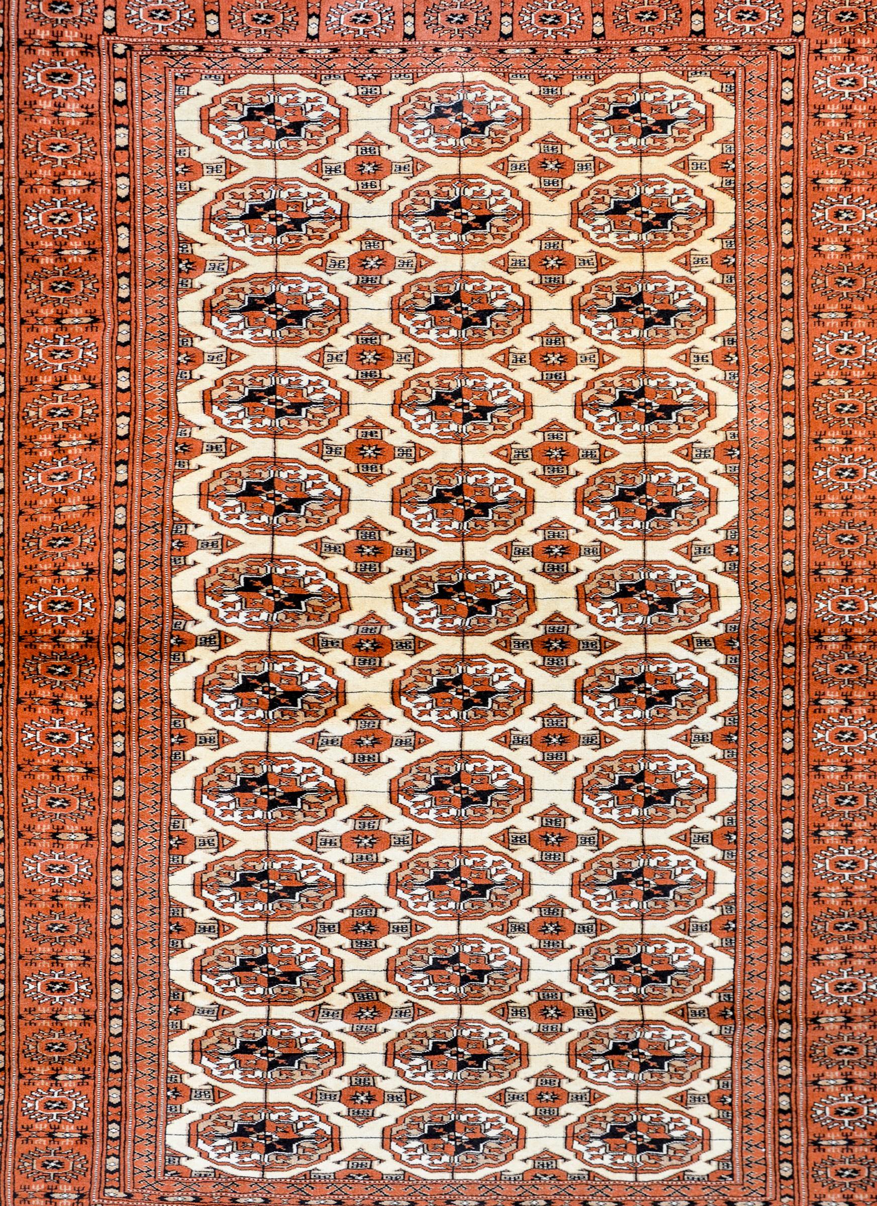 A fantastic vintage Persian Turkoman rug with an all-over field of floral medallions woven in white, cream, brown, and black colored wool surrounded by a wide border of multiple floral patterned stripes.