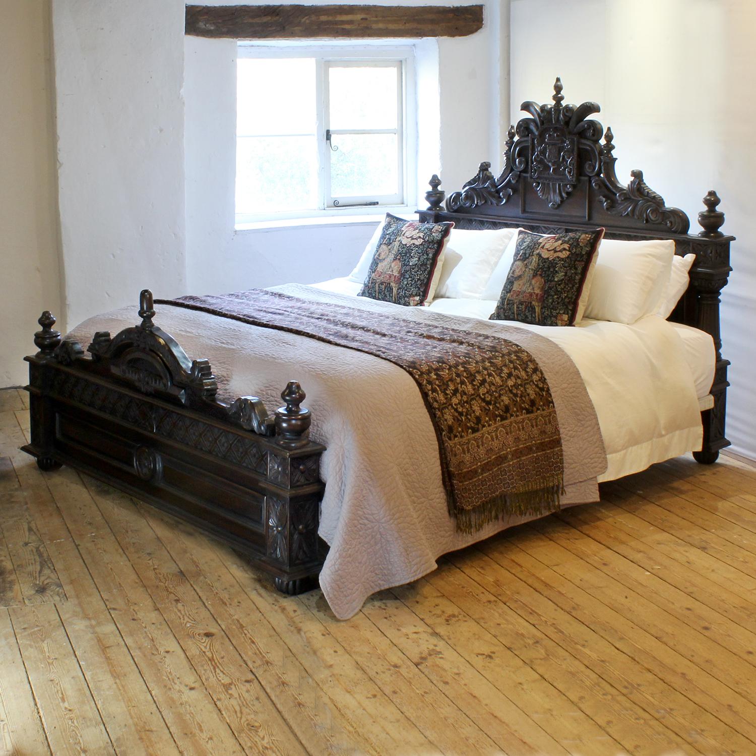 A fantastical carved vintage wooden bed in dark hardwood with a coat of arms carved in the centre of the head panel. 

This bed accepts a Californian King or UK Super King, 6ft wide (72 in), base and mattress set.

The price includes a firm bed base