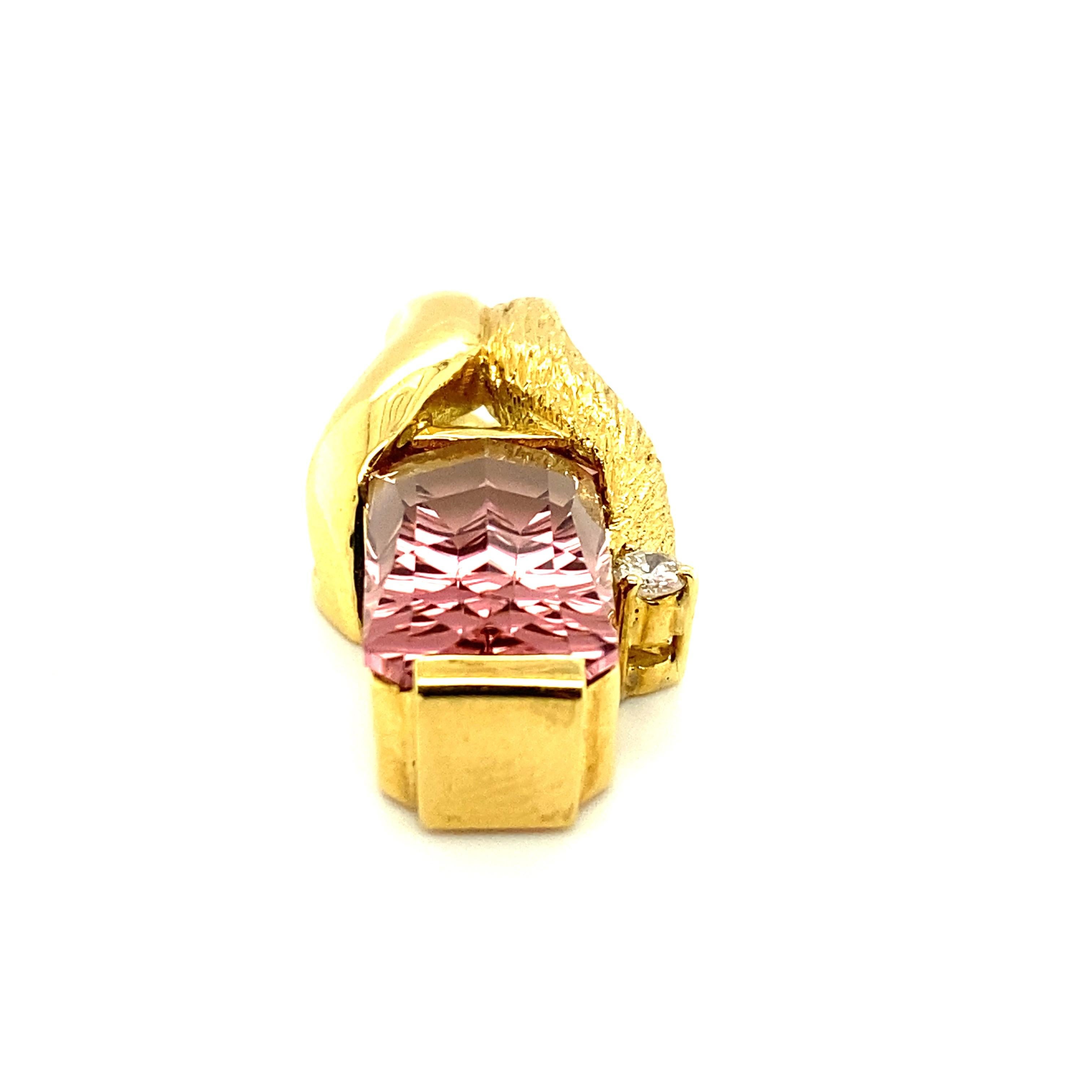 A multi-textured 18k gold pendant built around an approximately 13ct pink tourmaline with a modern fantasy cut designed to enable light to reflect back through the stone in what could almost be termed a starburst pattern.  The pendant mounting