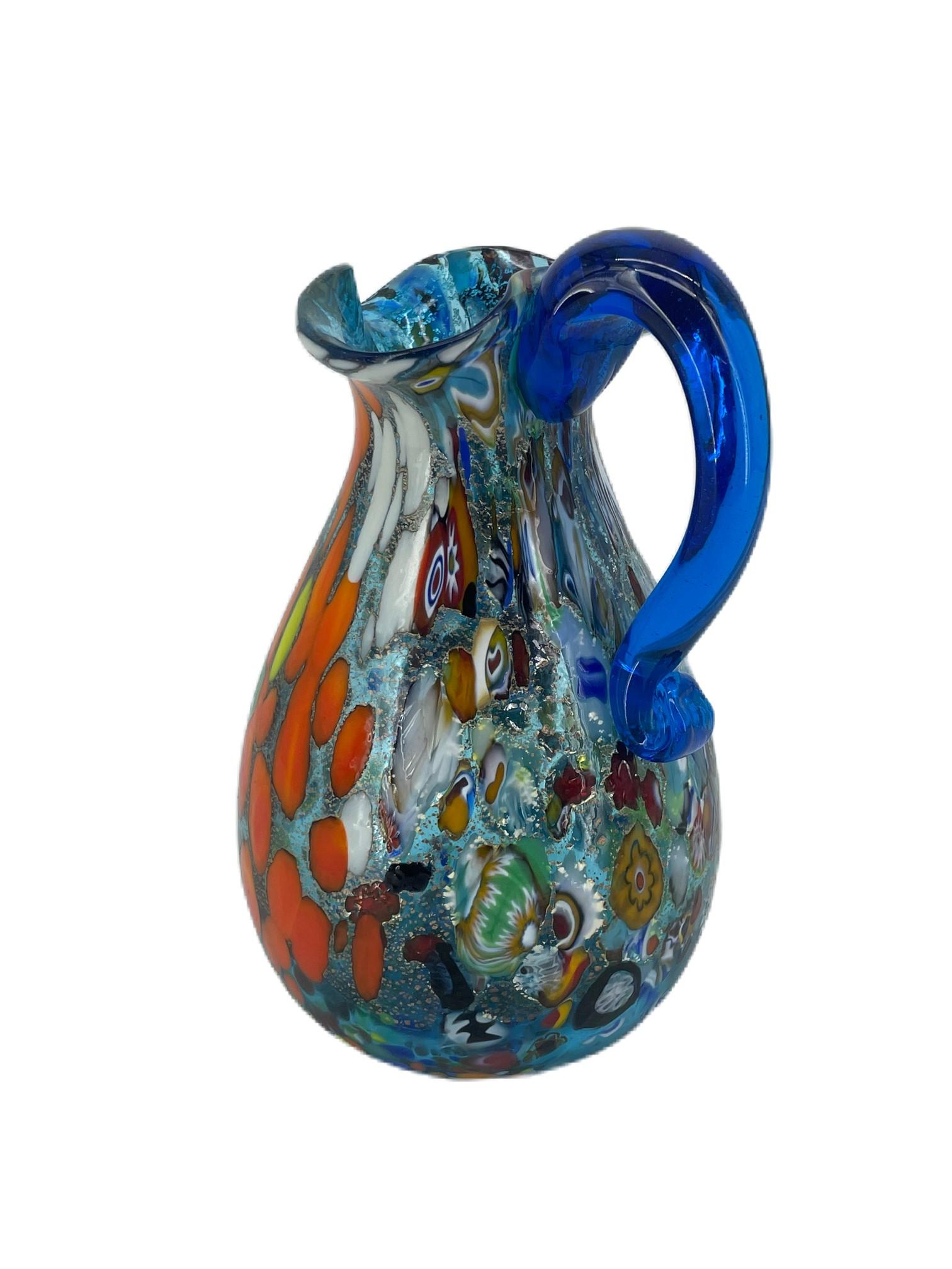 Pitcher from the ‘Fantasy’ Collection in aquamarine Murano blown glass with assorted multicolour “Mace” decoration, Murrina Millefiori and silver foil.
The vase has been hand-crafted by Murano master glassmaker Imperio Rossi.
Original Murano Vetro