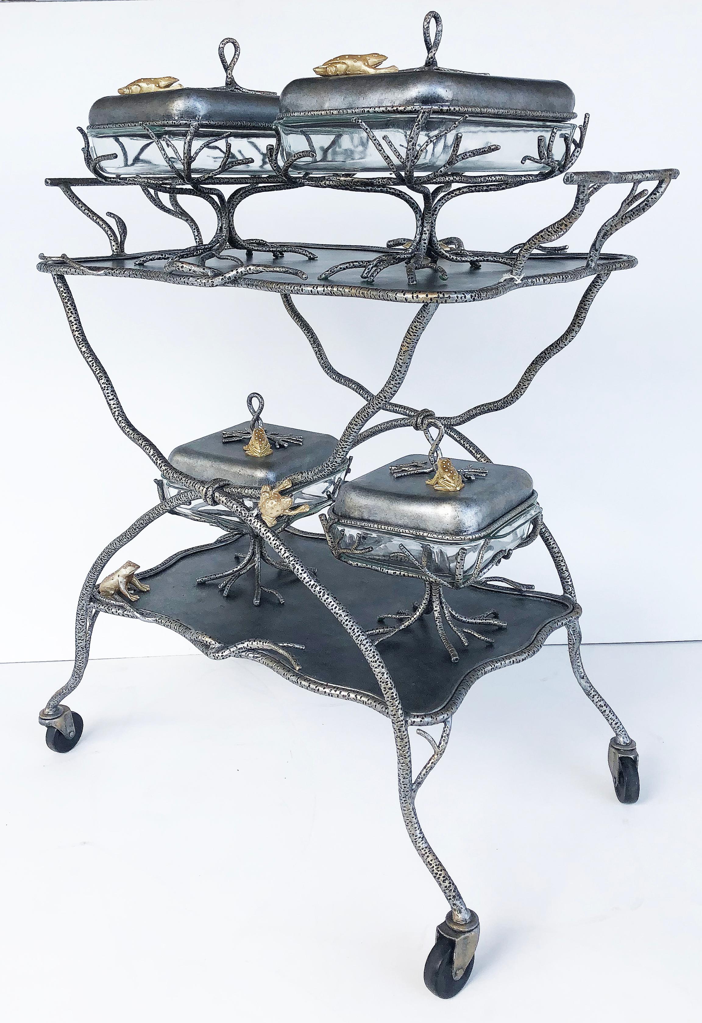 Fantasy Studio pewter serving cart with frog covered serving dishes set.

Offered for sale is a pewter two-tiered serving cart in the form of branches embellished with gilt frogs. This is probably a one-off studio fantasy piece with a Brutalist