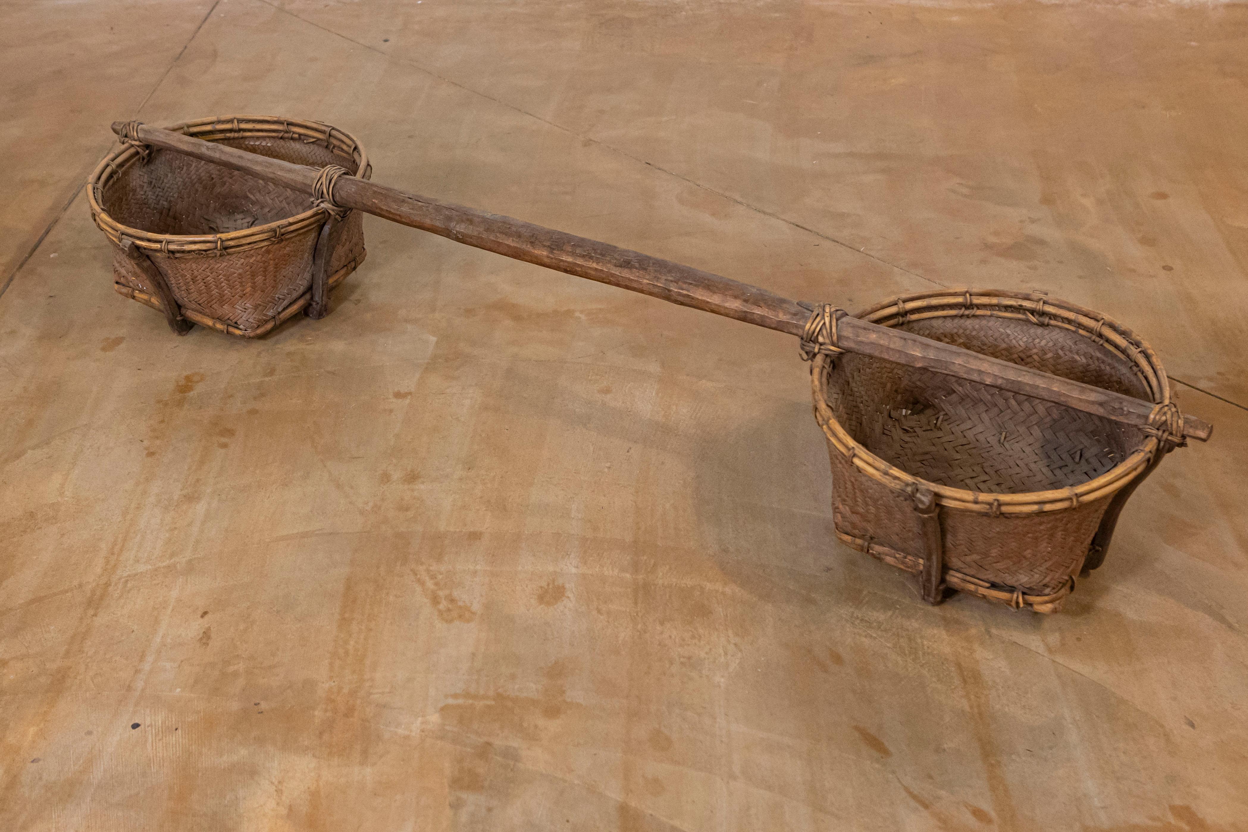 Un giogo da spalla dell'Estremo Oriente dell'inizio del XX secolo, con cesti in rattan e bambù. Questo giogo da spalla dell'Estremo Oriente ci affascina con la sua storia e il suo aspetto ben conservato, con un'asta di legno centrale collegata a un