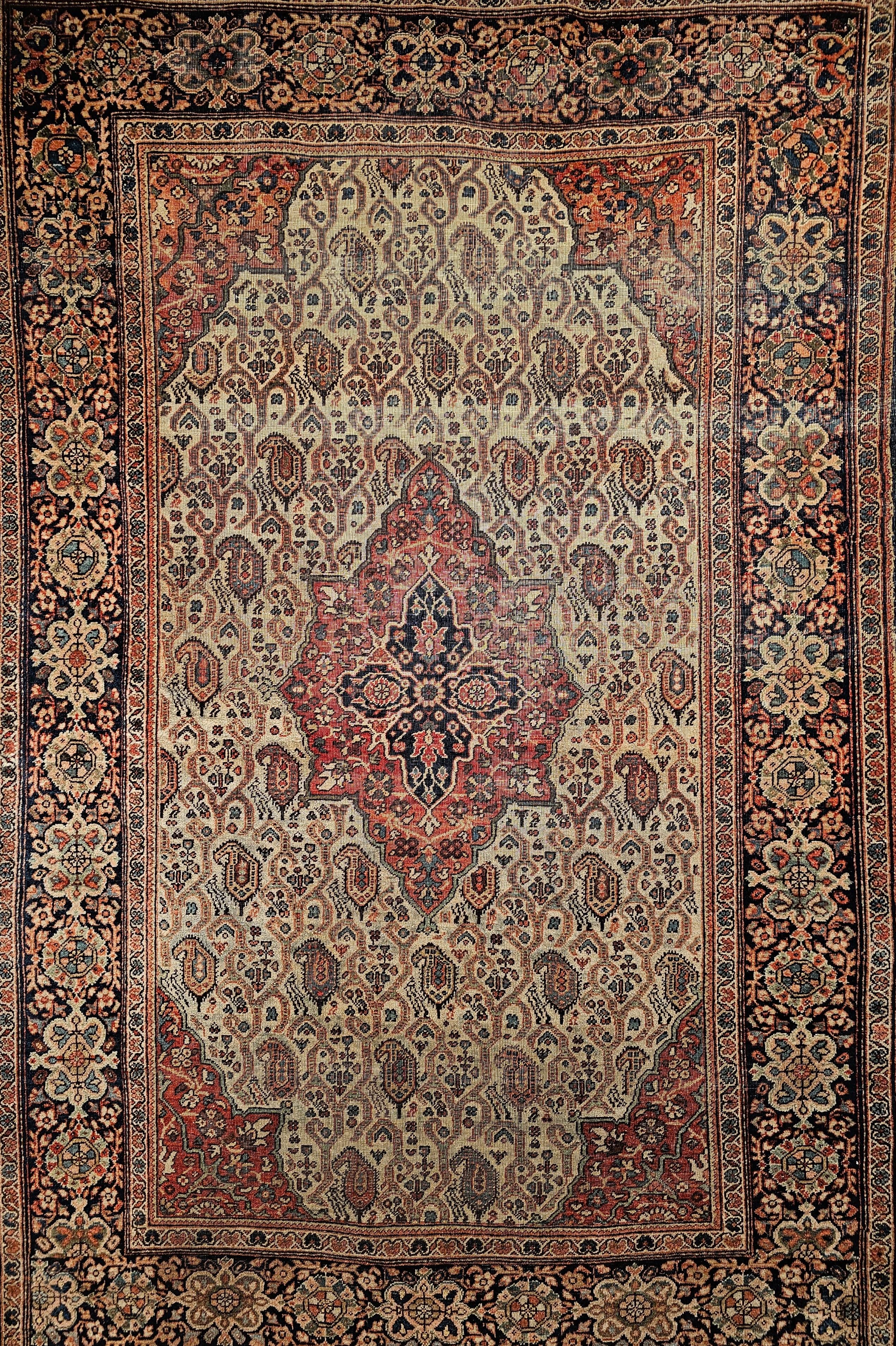 Late 1800s Persian Farahan Sarouk area rug in an allover paisley pattern in a pale green field with a rust red border.  The rug has a very unique all-over paisley design connected via scrolling lines set in a pale pistachio green field color with