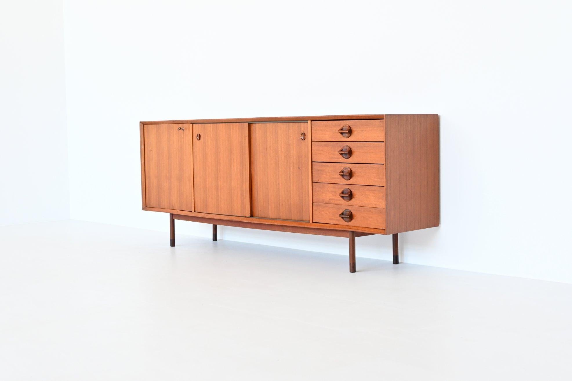 Beautiful sleek shaped sideboard model “Monika” designed and manufactured by Faram, Italy 1960. This sideboard is made of nicely grained teak wood supported by a solid teak wood frame with rosewood feet tips. It has two reversible sliding doors and