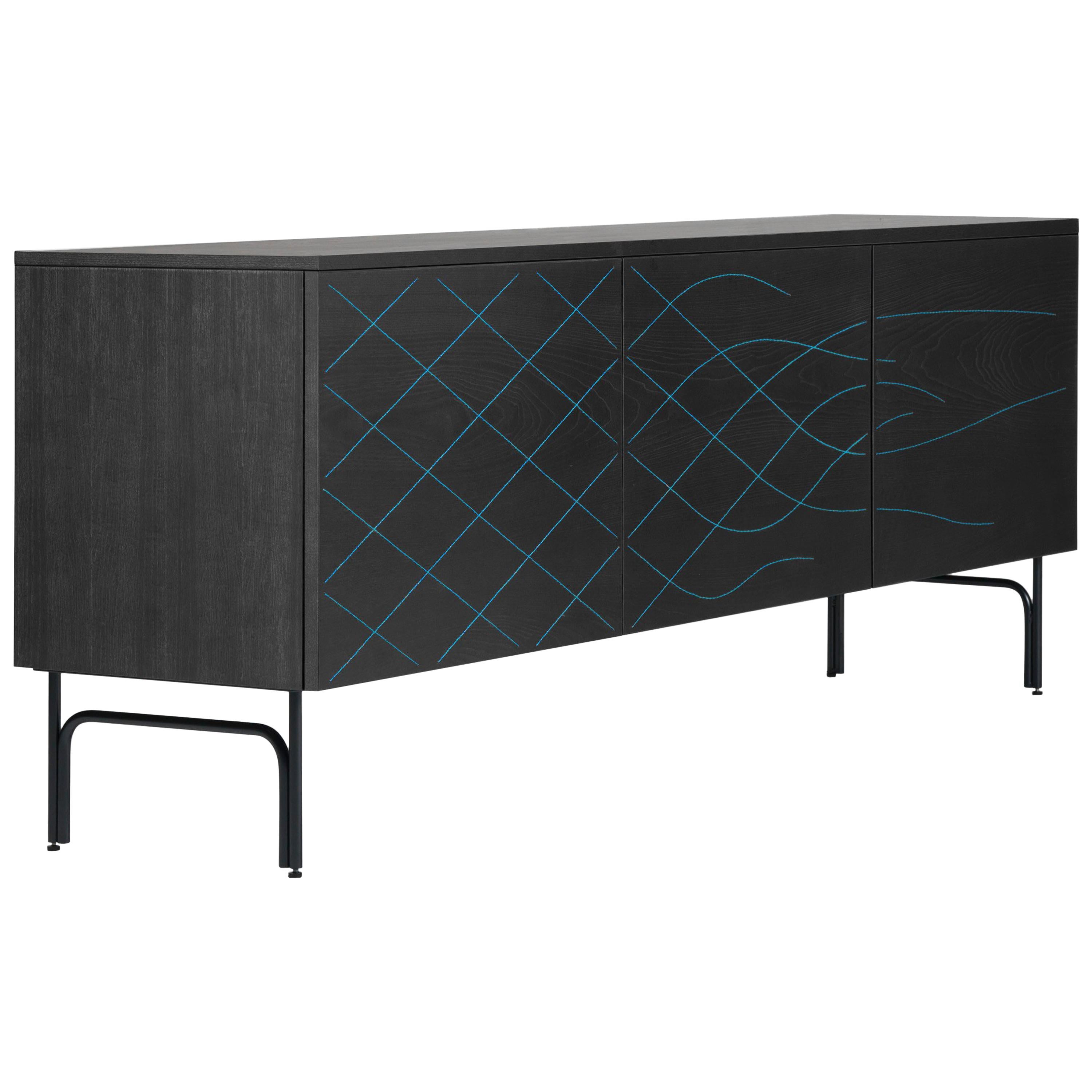 Cabinet designed by Färg & Blanche manufactured by BD Barcelona.

Manufactured in natural ash wood or stained in black. Structure in anodic black lacquered steel. The doors carry simple patterns made using the Wood TailoringTM technique. Blue