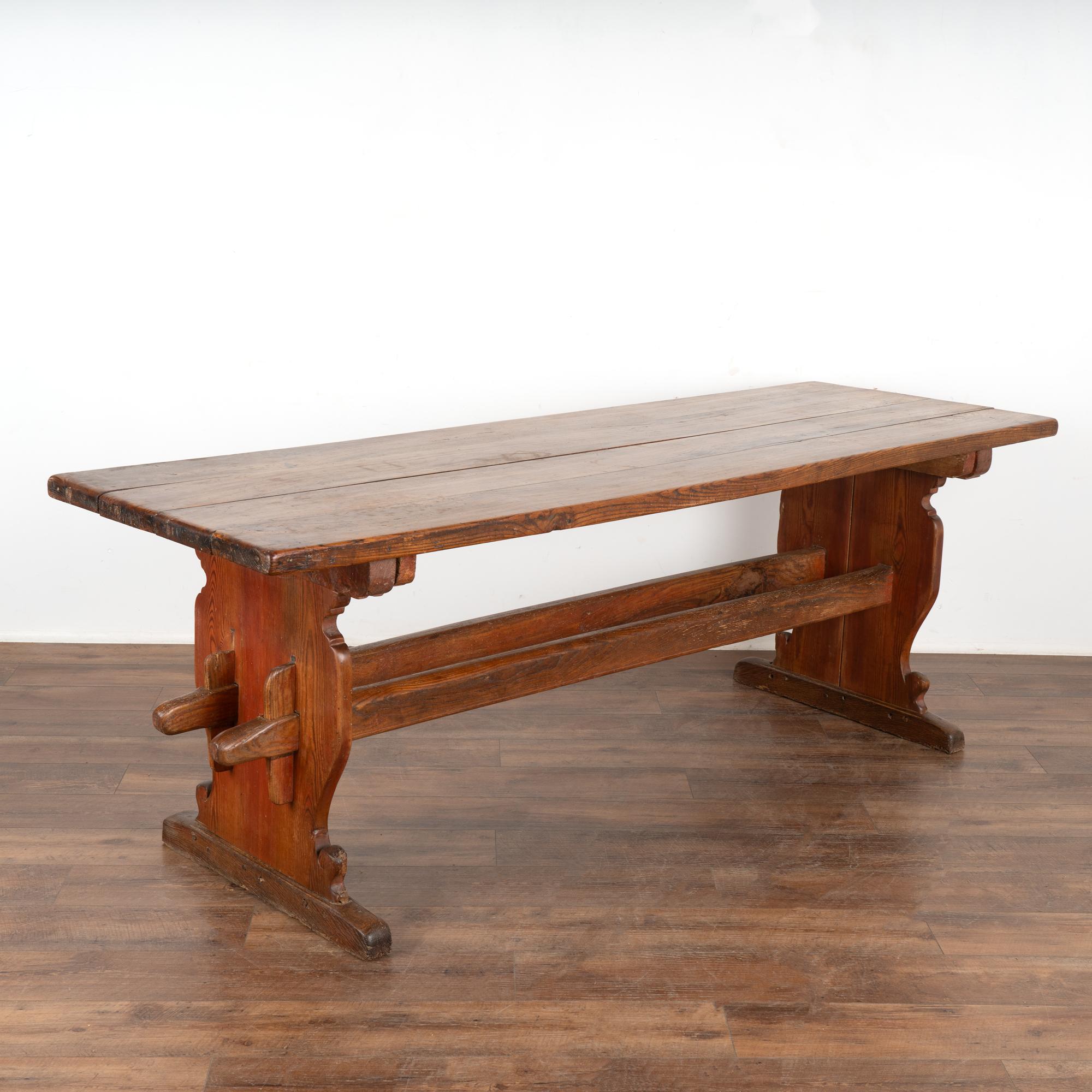 This old farm table is loaded with aged patina and warmth that come from generations of use.  
As seen in photos, the rich brown has touches of red around the side legs/stretchers. 
Restored, strong and stable, this 7' table is ready to be used and