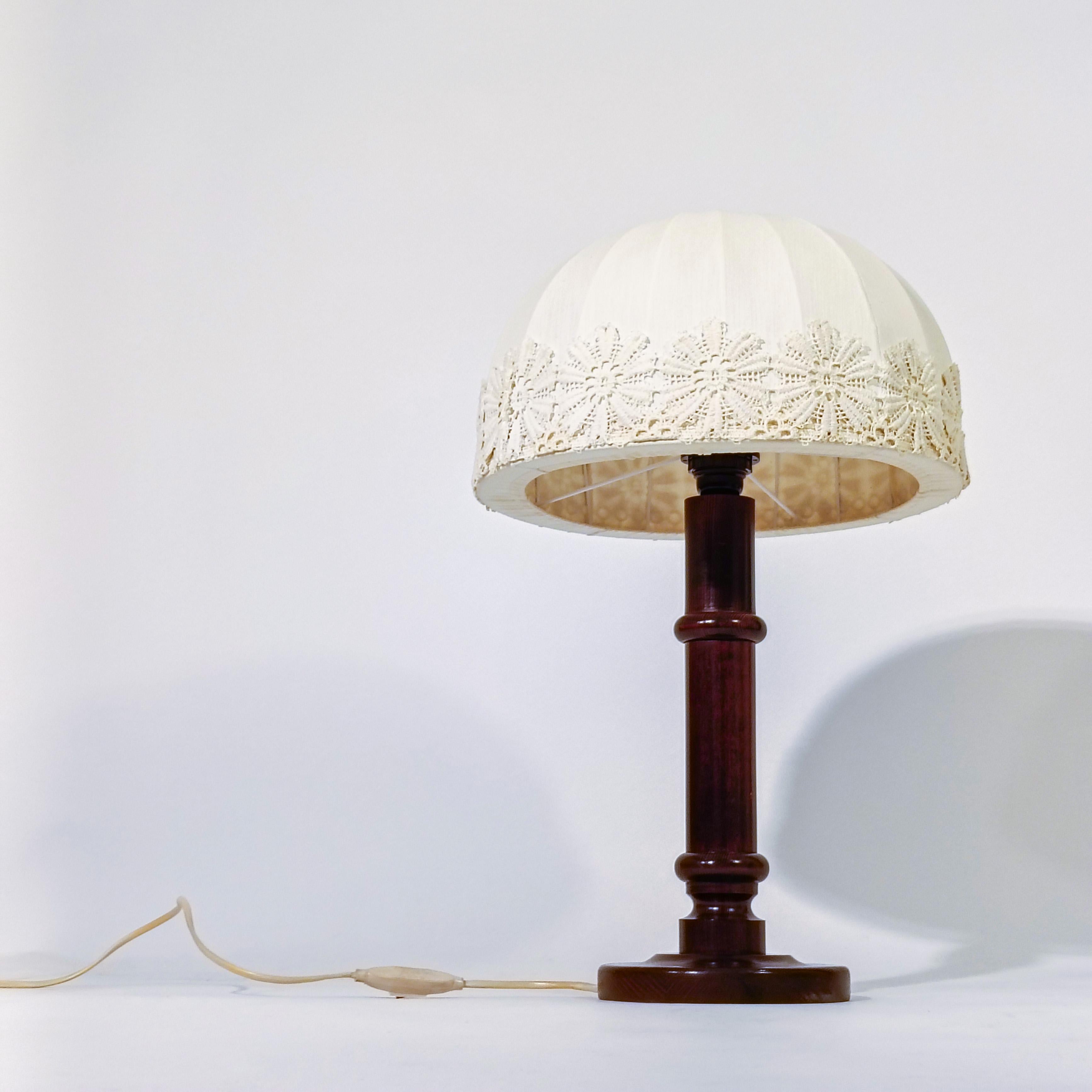 Linen and embroidery table lamp from Markslöjd AB, Sweden, 70s. Made of turned pine wood and varnished in chocolate tone, with its original Cocoon style lampshade made of linen with a sewn lace border and hand embroidery. Very warm piece, through