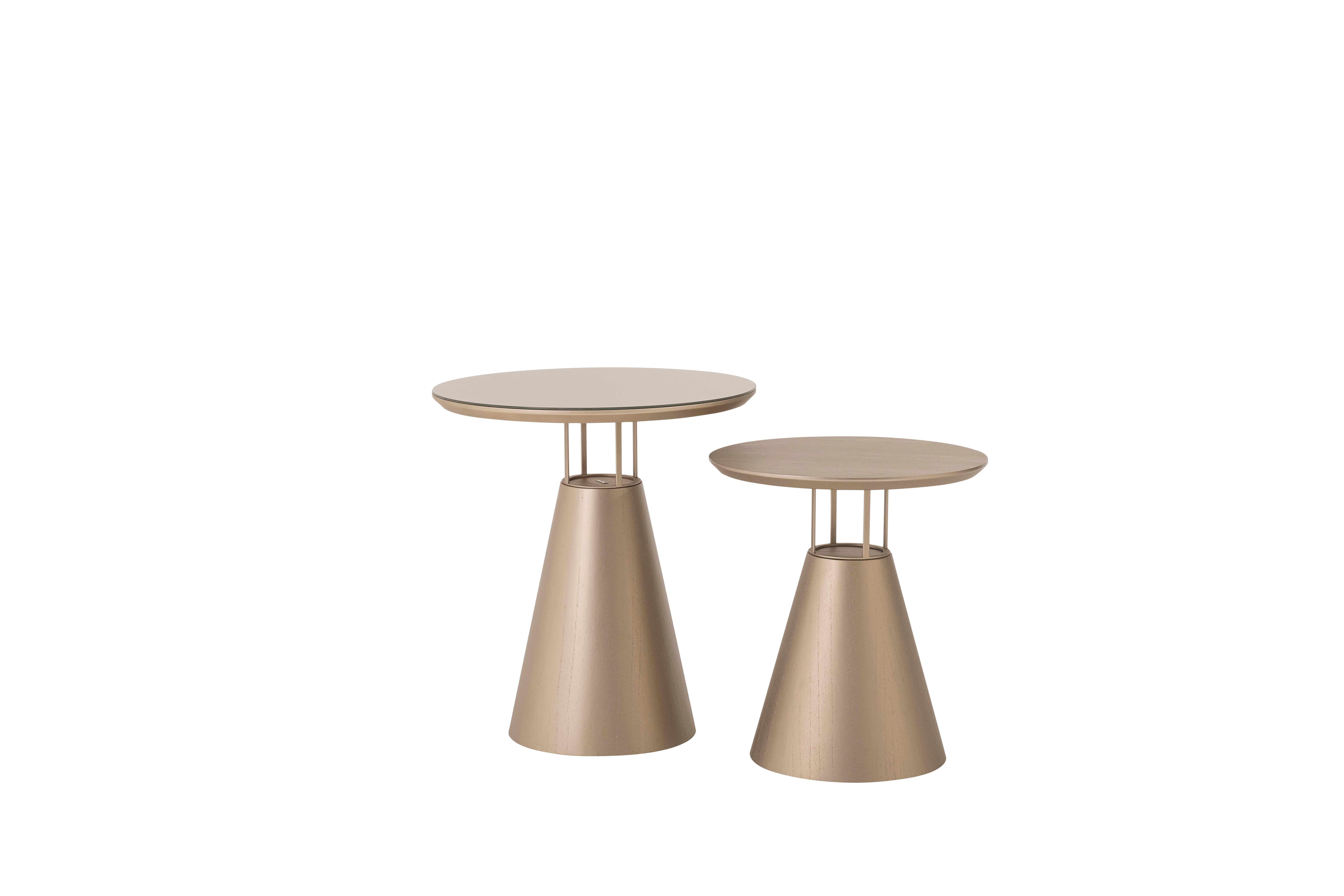 REF. SMM 1070
Design/One contemporain et élégant.
La table d'appoint Farol a un design de base en forme de cône, en fibre de verre recouvert de placage de bois de cannelle naturelle peint avec une peinture laquée mate dorée, et des détails en acier