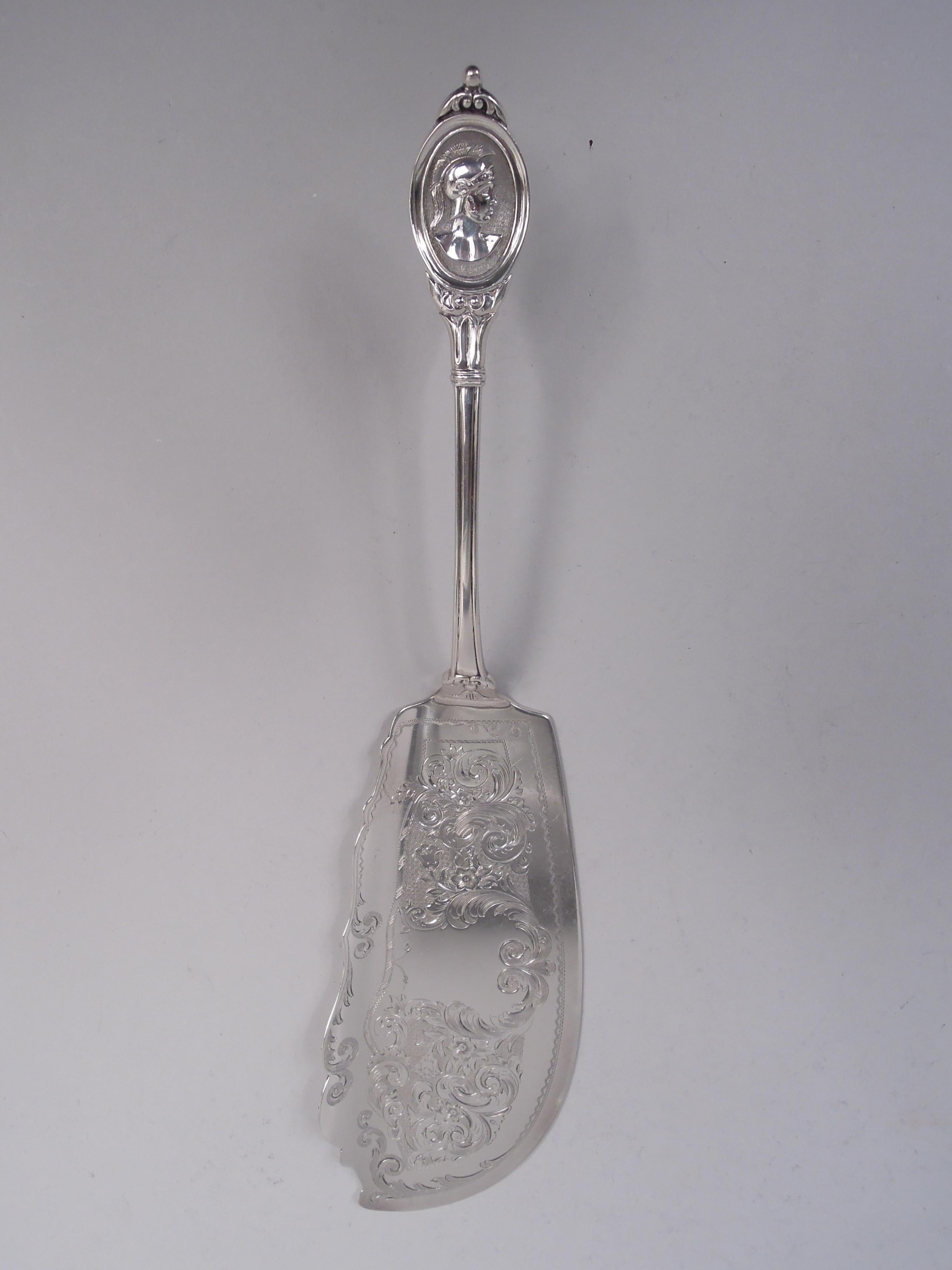 Medallion coin silver fish serving pair, comprising fork and slice. Made by Farrington & Hunnewell in Boston, ca 1850. Terminals have right-facing centurion in stippled oval with bead-and-leaf mounts. Fork has scrolled and open shank. Slice has