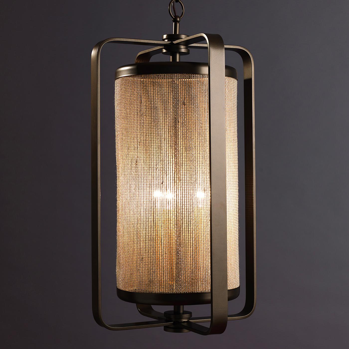 Ispirato allo stile minimalista e affascinante degli anni '60, questo lampadario è stato progettato dall'Officina Ciani e dallo Studio A. Ciarmoli Queda. La struttura in ottone presenta un telaio cilindrico racchiuso in quattro elementi a forma di