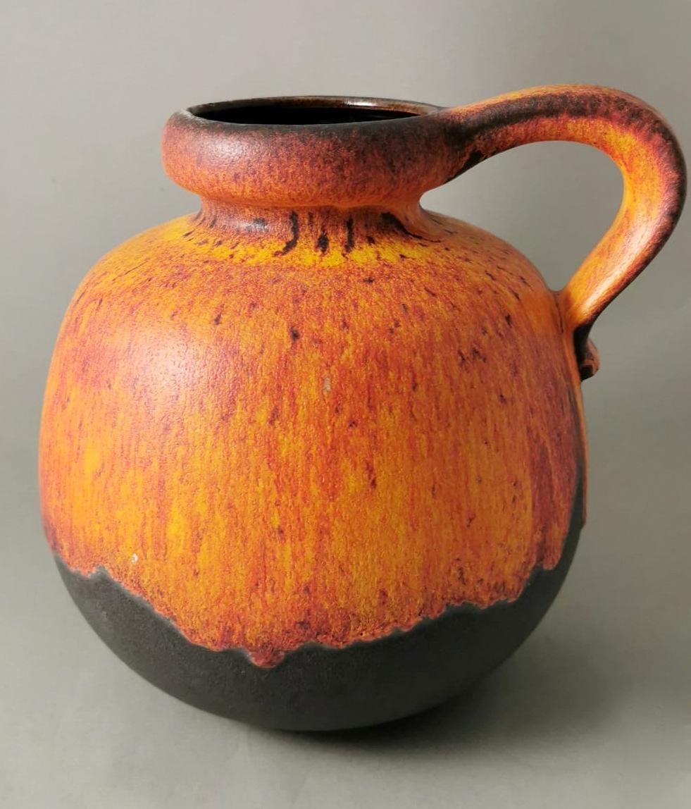 We kindly suggest that you read the whole description, as with it we try to give you detailed technical and historical information to guarantee the authenticity of our objects.
Peculiar and original German orange and black colored ceramic pitcher;