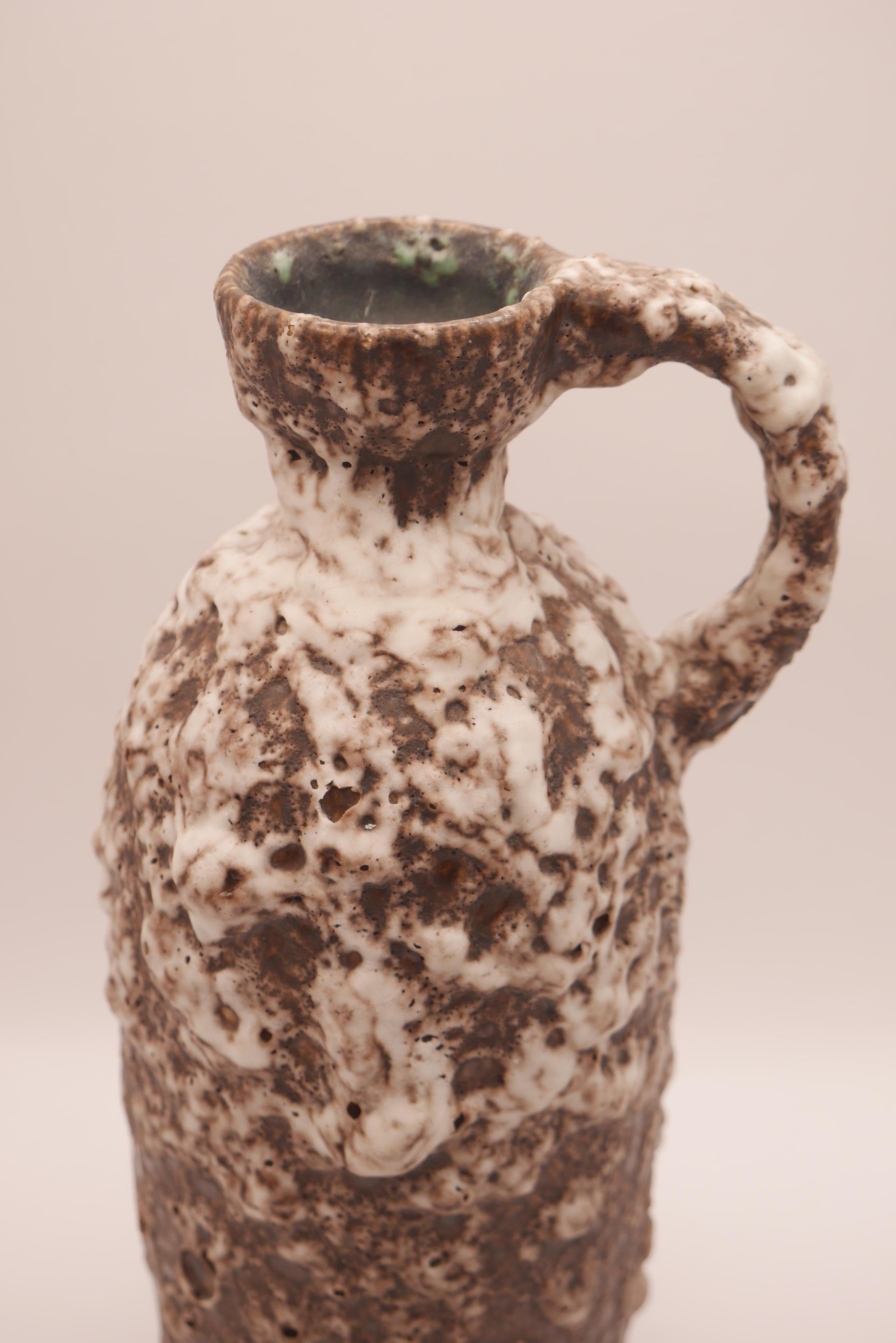 An unusual handled vase with a cracked, fat lava glaze in gray, brown and white.
Model number 327/3

West Germany art pottery:

Between 1949 and 1990s, the term West German Art Pottery became the way to describe German pottery because the