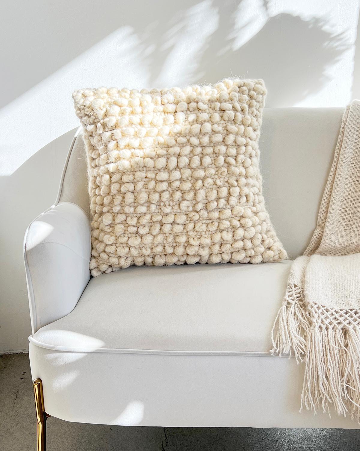 A textured throw pillow for your living room couch. This unique throw pillow features rows of bobbles (balls) made with 100% undyed sheep wool for a truly textured and cozy look. These cushions are handmade by Fatima in Portugal with wool from local