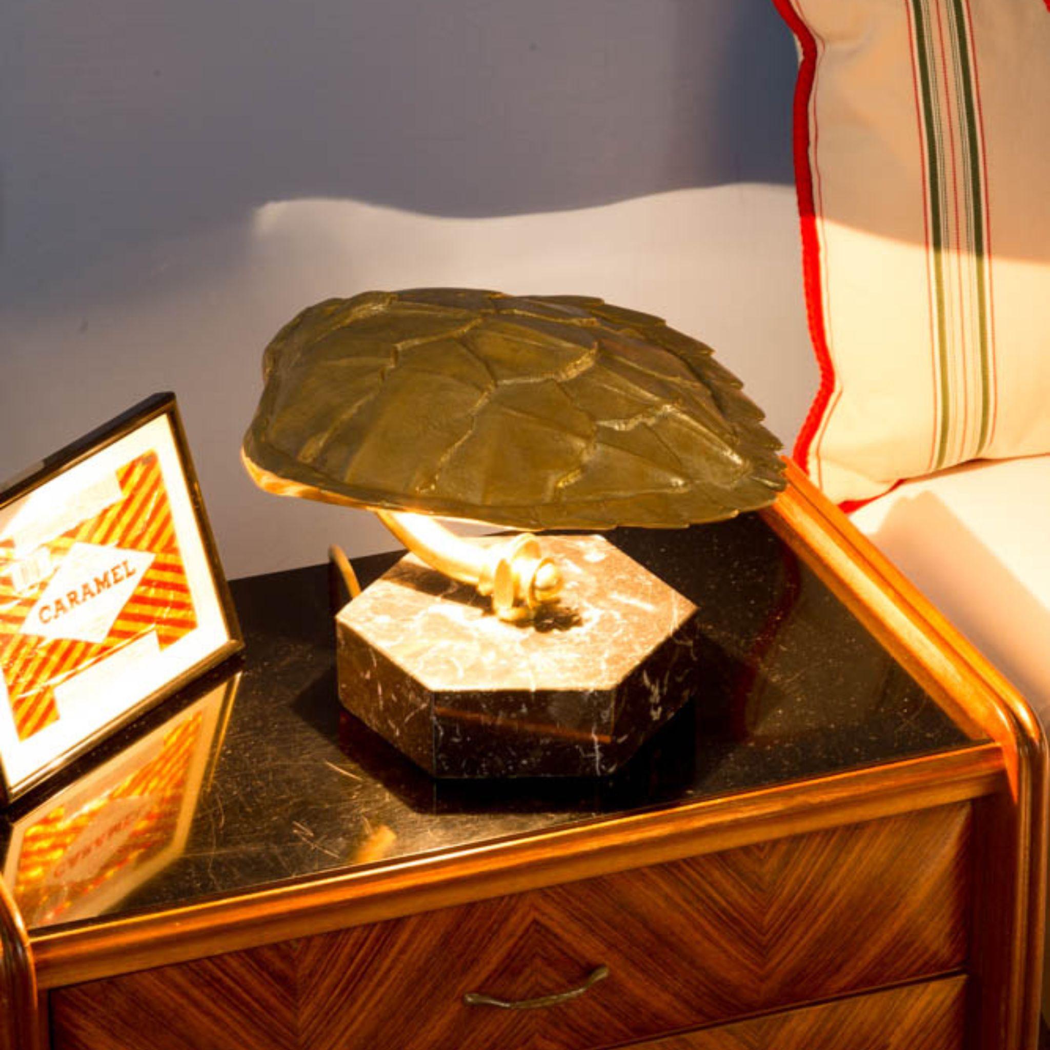 This table lamp belongs to the Fauna line of the Eclectic collection, it has a casted brass turtle shell, natural finish, on an exagonal black Marquinia marble base. The table lamp can be customized either in the marble base color and brass
