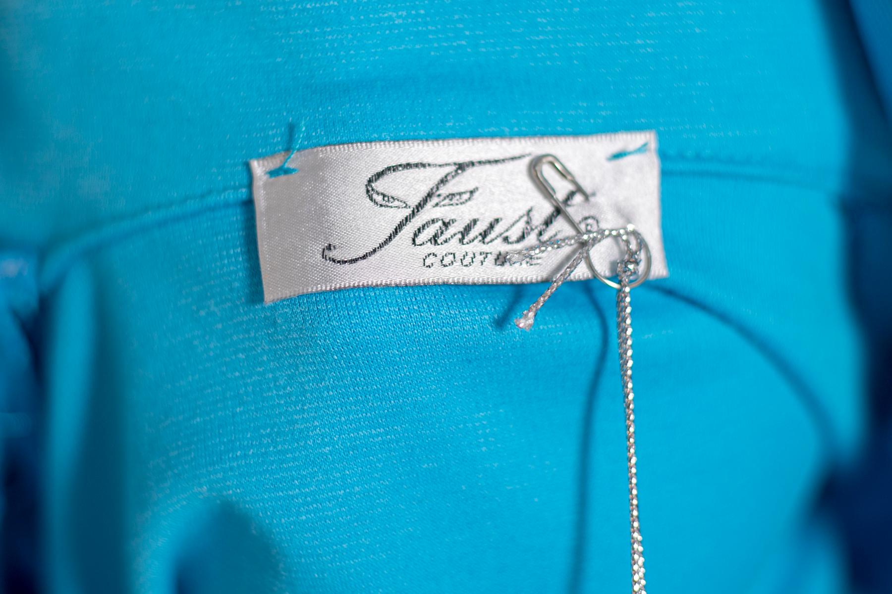 Wonderful elegant turquoise dress by Faust from the 1990s, made in France. ORIGINAL LABELS.
The dress is short, above the knee and is turquoise in color. It has long fine sleeves. the collar is high and the highlight of the garment. In fact, it is