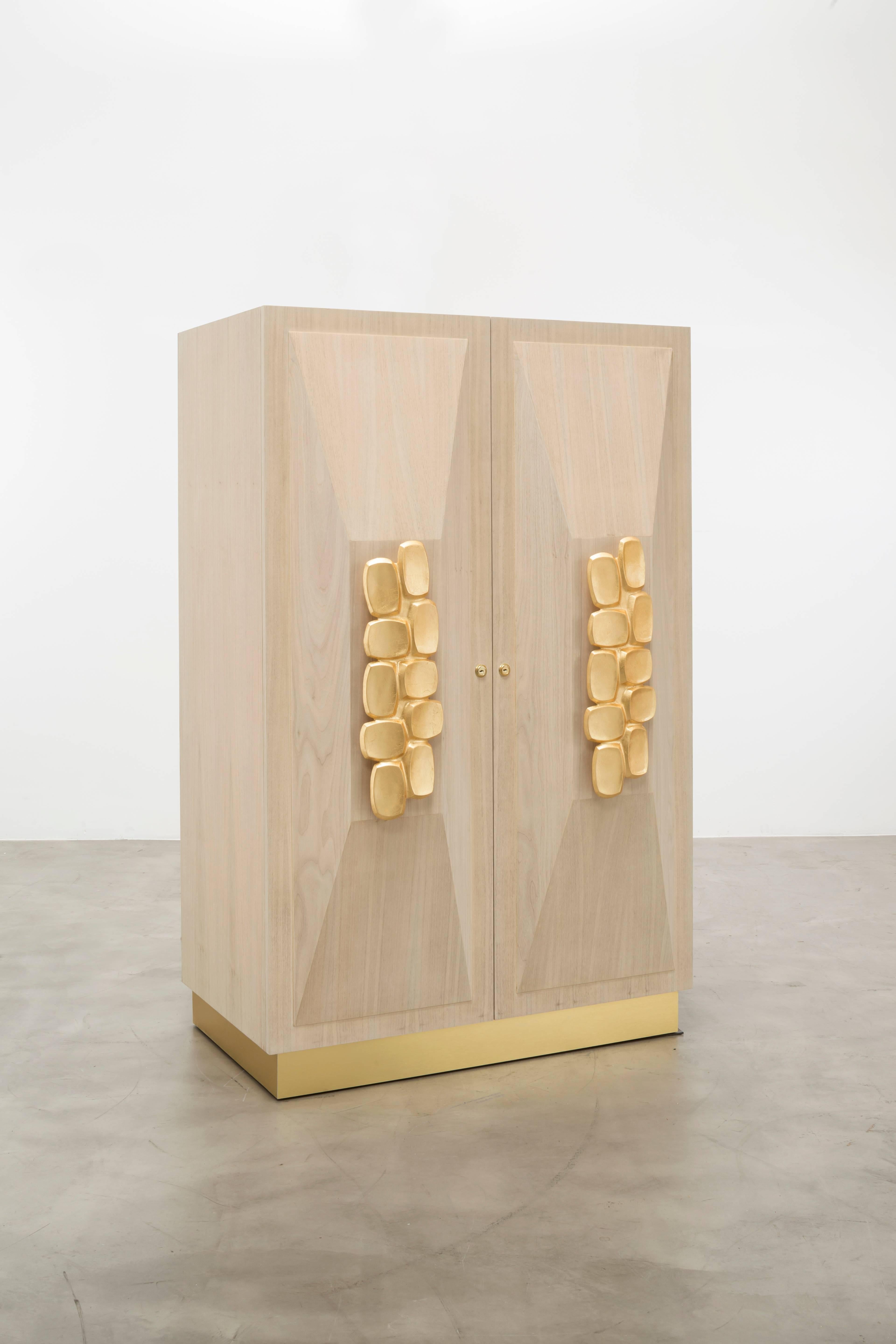 The Faustine jewelry cabinet features a bleached walnut body with hand-carved walnut applique door details and hand-forged leafed handles perfect to store all your most precious and expensive jewels, watches and keepsakes. This cabinet locks for