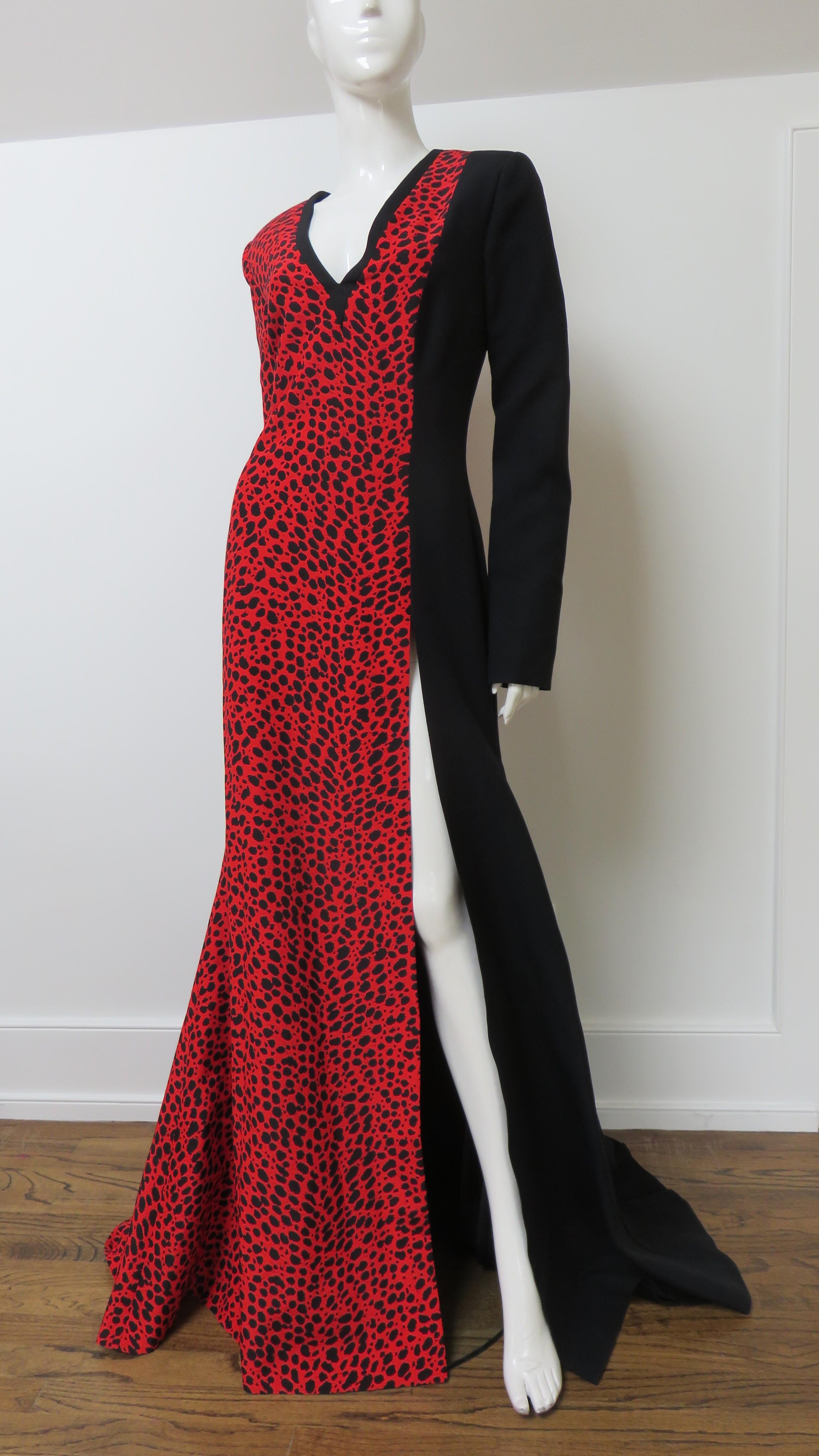 Un bellissimo abito in seta bicolore di Fausto PUGLISI. È semi-aderente alla vita e presenta una scollatura a V, maniche lunghe e una gonna completa con uno spacco lungo una gamba.  Ciò che lo distingue è la divisione tra il tessuto a motivi