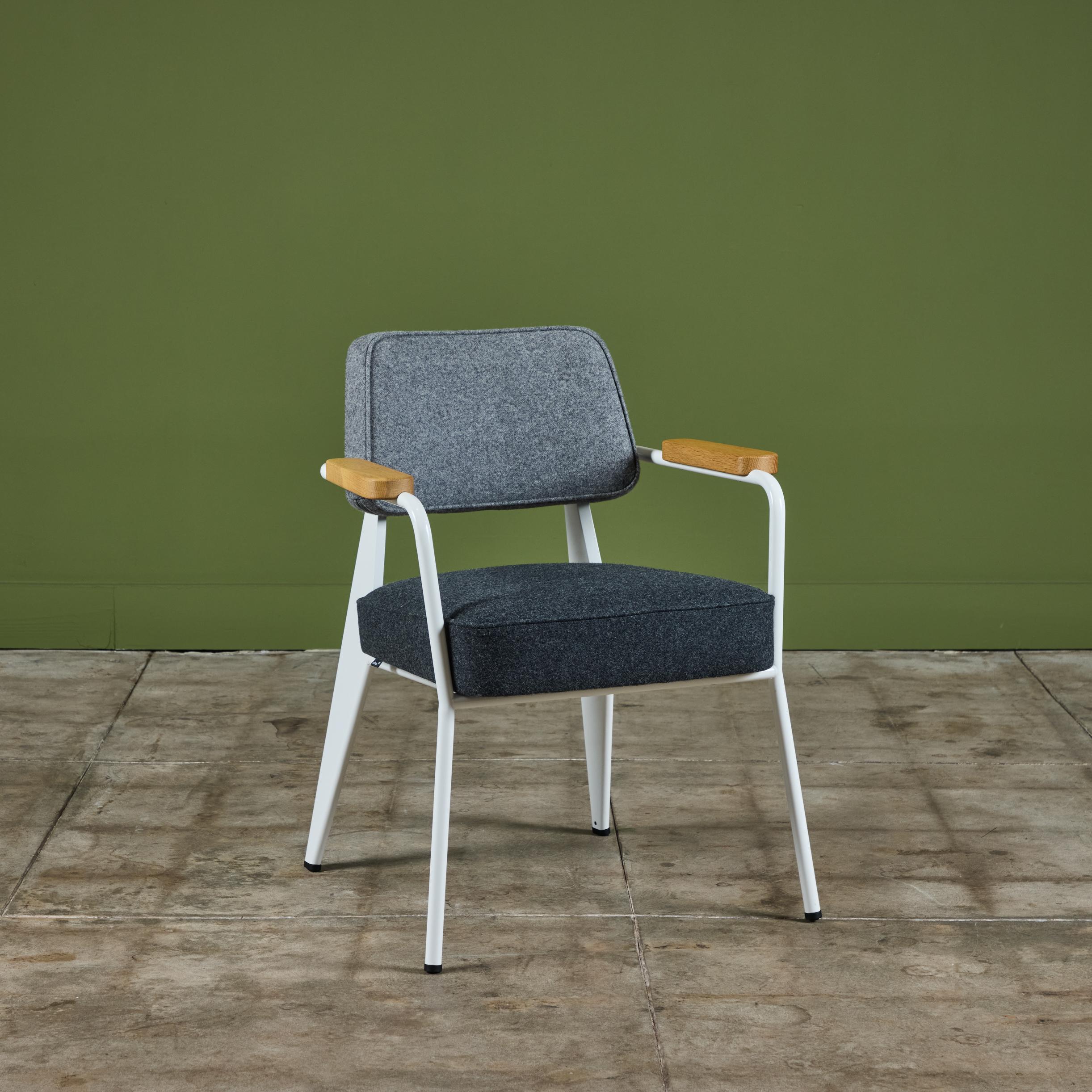 Armchair by Jean Prouvé, originally designed in 1951 this example was produced in Switzerland by Vitra in 2019. This chair features a white enameled steel frame with oak arm rests. The chair is upholstered in Maharam wool fabric with a lighter gray