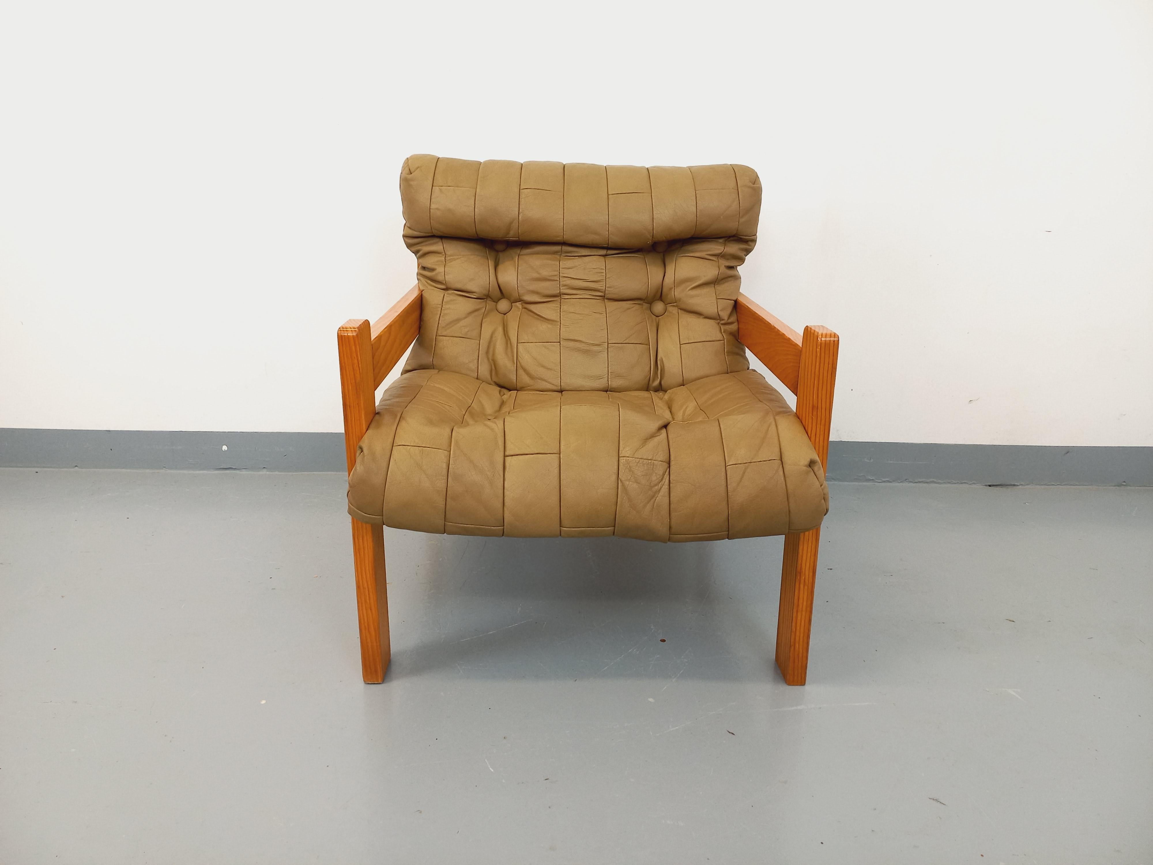 Fauteuil chauffeuse vintage des années 70, en bois de pin, dossier et assise en cuir capitonné couleur sable, tissu tendu à l'arrière, très beau design dans le goût de Pierre Boi, vis apparentes en laiton, très confortable, bon état général avec