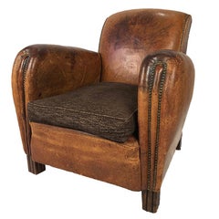 Fauteuil club recouvert de cuir fauve, finition clous tapissier, époque art déco