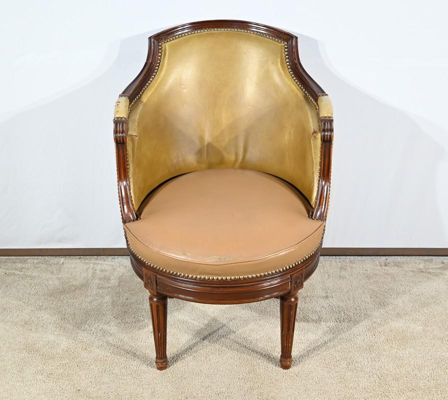Questa sedia da ufficio girevole in faggio color noce poggia su quattro gambe tornite con scanalature fisse.
Lo schienale a forma di gondola è ornato da una traversa a forma di cappello, mentre i braccioli sono a righe e intagliati a volute.
I