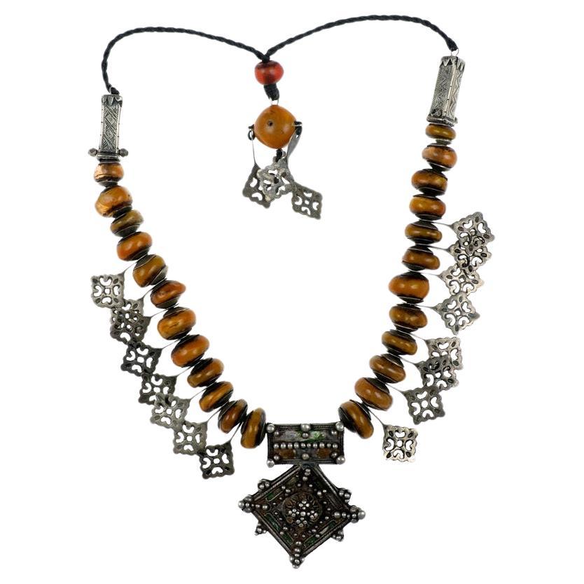 A Custom Made Necklace by Famous Moroccan Jeweler Chez Faouzi of Marrakech. Necklace is made up of Antique Faux Amber Beads and Hand Tooled Antique Moroccan Silver Accent Charms with the Signature Faouzi Back Neck Charm. The Antique Moroccan Silver