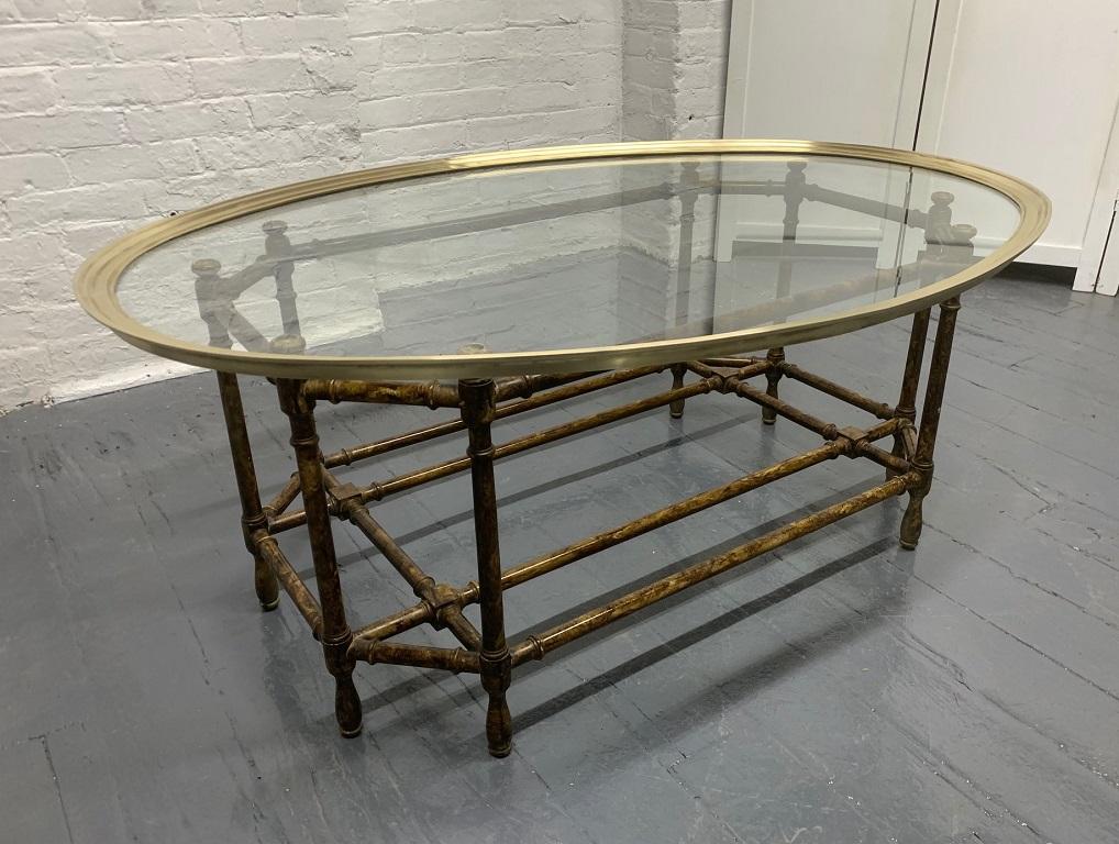 Faux bamboo and brass coffee table by Baker Furniture Company. Painted grain faux bamboo base with a glass and brass oval top.