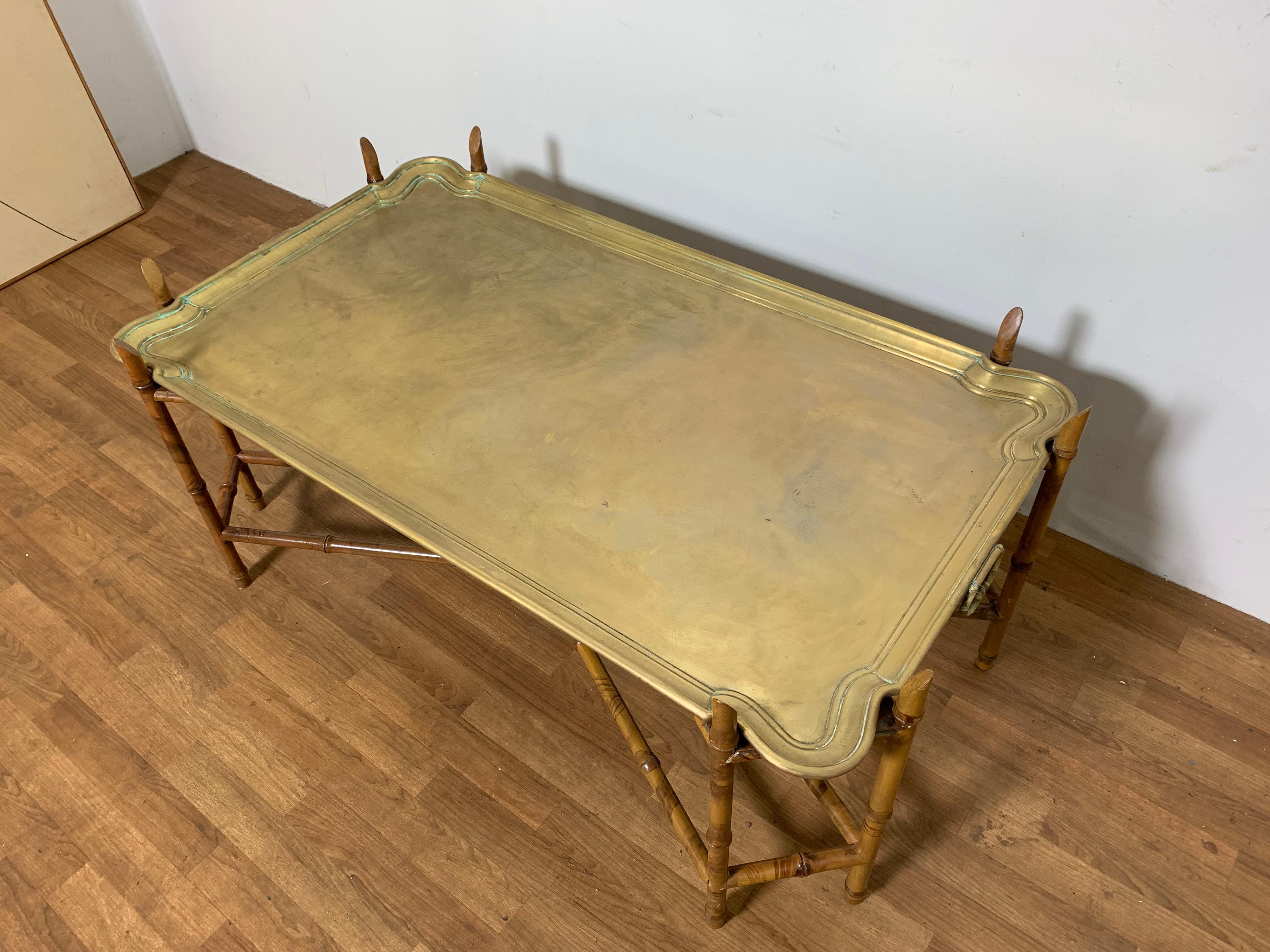 English or Hollywood Regency style coffee table attributed to Baker, featuring a removable brass butler’s tray atop a carved wood faux bamboo base, circa 1950s.
Measures: 21