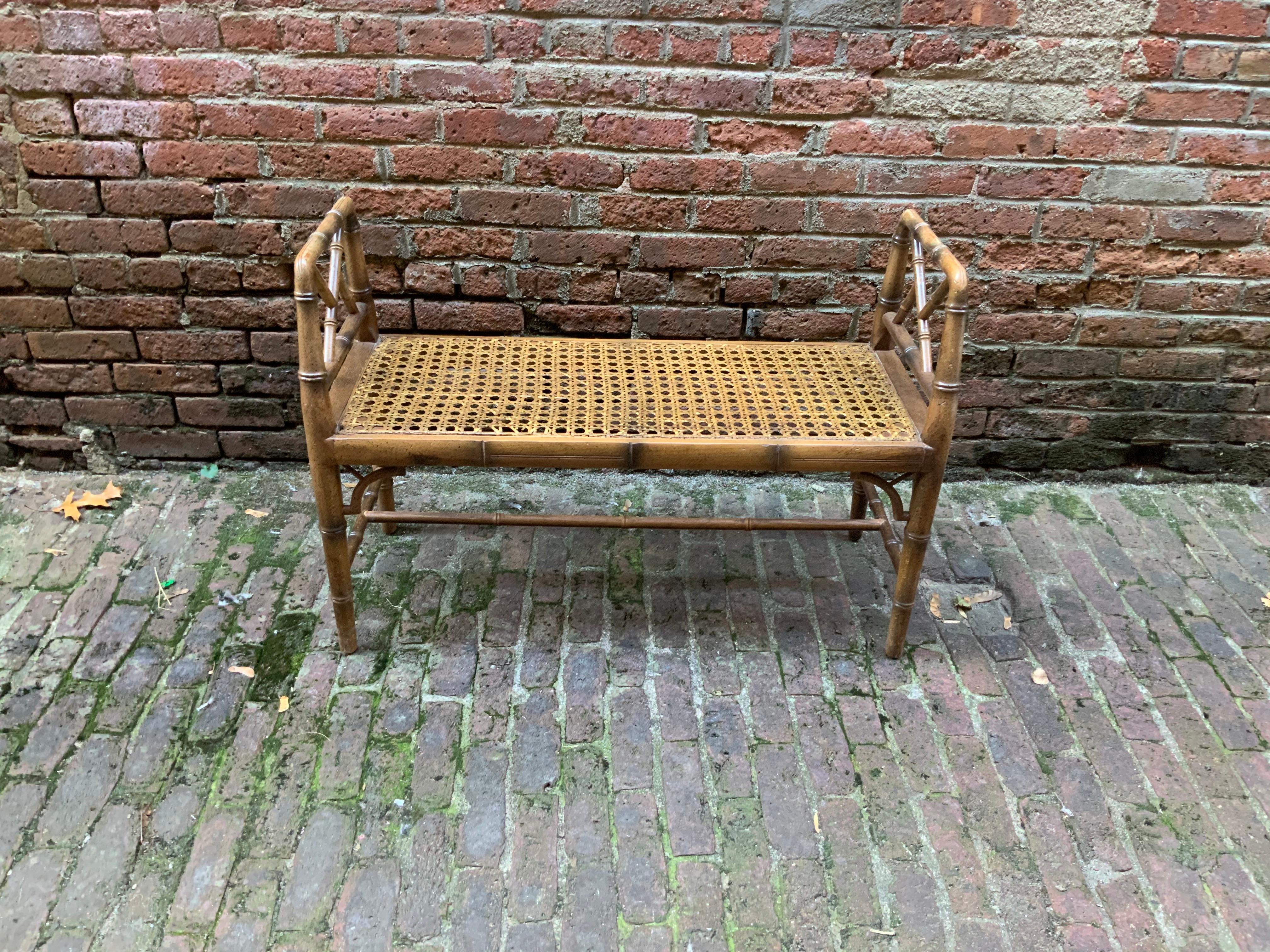 Faux bamboo and caned bench can go anywhere from a hall entrance to the foot of a bed, circa 1970. Very good condition with minor wear to the finish. The caned seat is still good and isn't sagging from age.