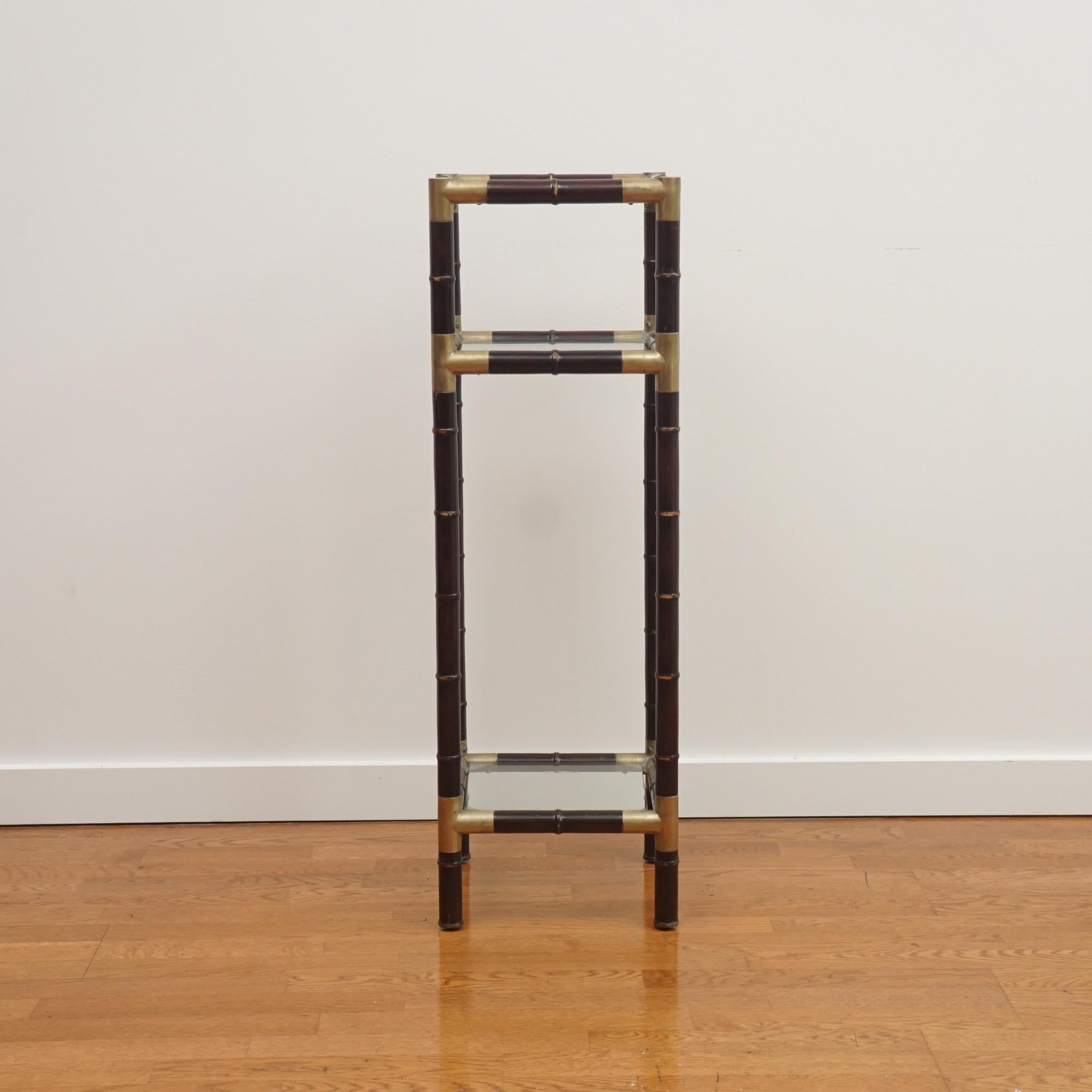 Der hier abgebildete Sockeltisch aus Bambusimitat ist ein Klassiker.  Der aus Mahagoni gefertigte Sockeltisch ist mit drei quadratischen Glasablagen ausgestattet.  Der dunkel gebeizte Rahmen aus Bambusimitat wird durch Eckteile und Gelenke aus