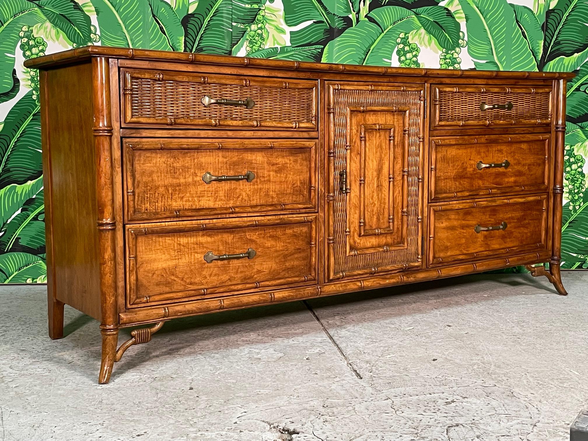 Vintage faux bamboo dresser features splayed legs, wicker veneered drawer and door fronts, and a rich, glossy finish. Good vintage condition with minor imperfections consistent with age (see photos).

 