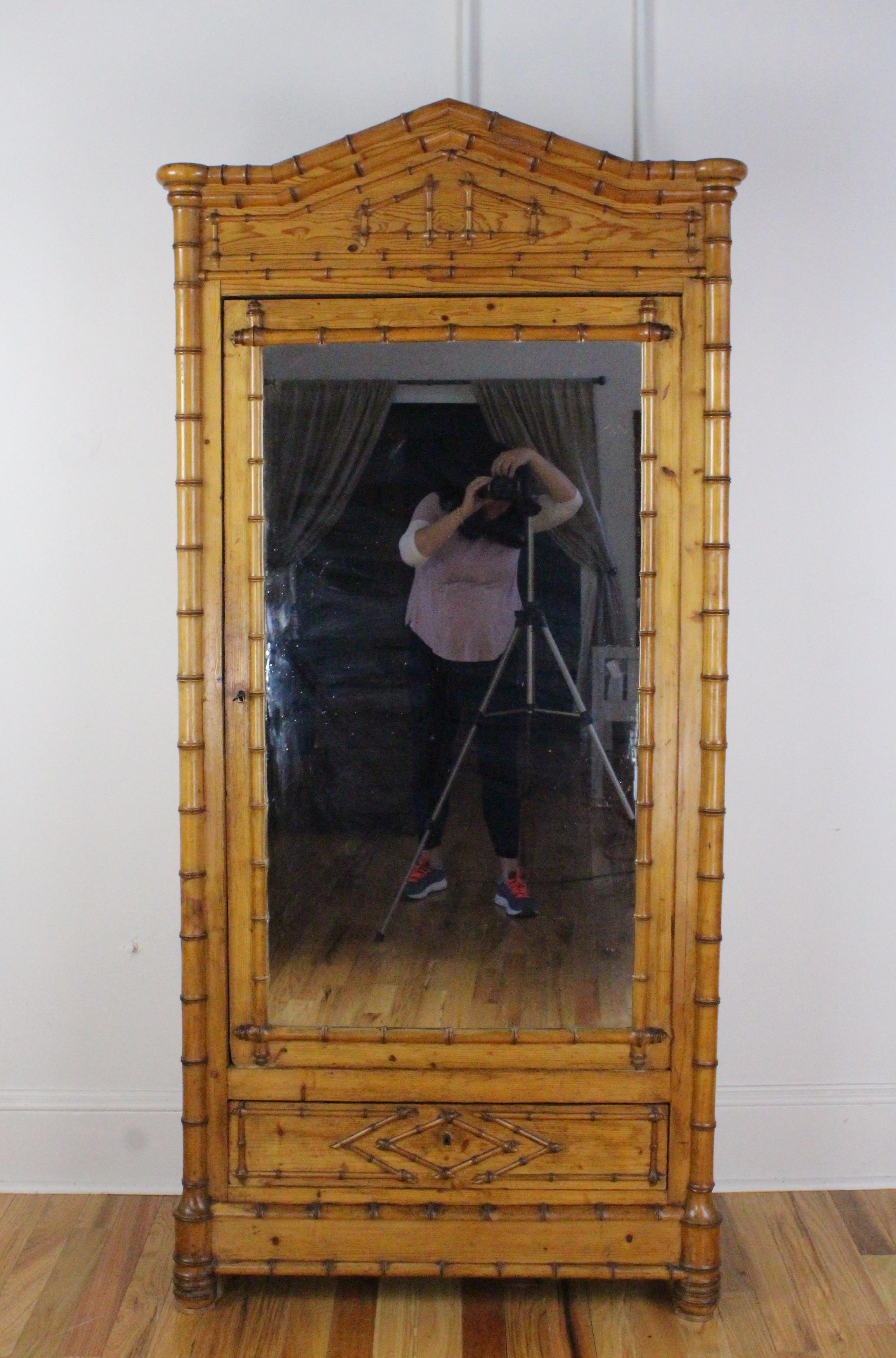 Une grande et imposante presse ou armoire en faux lin de bambou de couleur miel provenant d'Angleterre. La pièce est dotée de deux étagères réglables, et d'un large tiroir inférieur. La corniche et le tiroir inférieur présentent des détails en bois