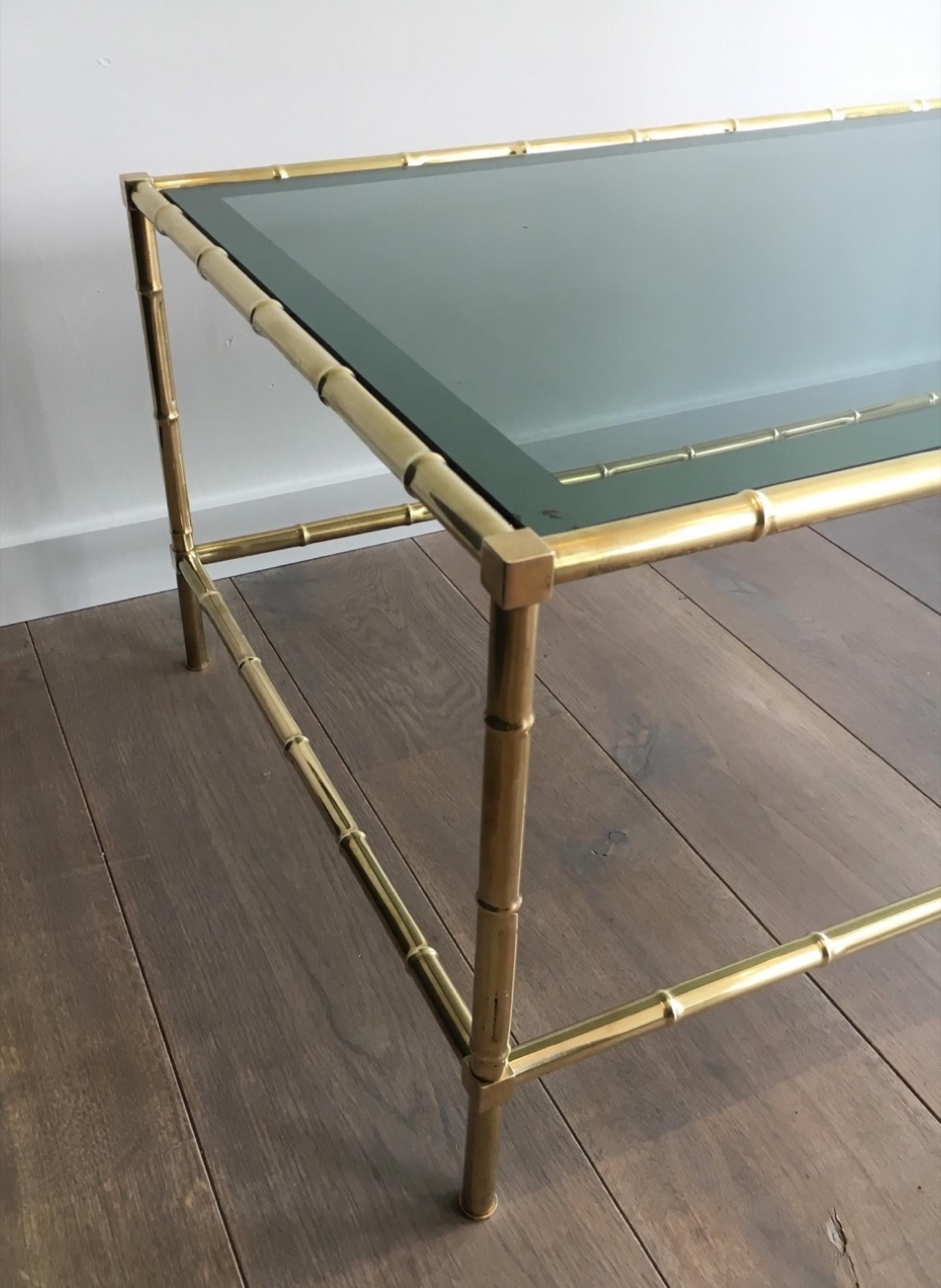 This faux-bamboo coffee table is made of brass with a blueish glass top. The surrounded silver part is a little bit used on some areas. This is a French work, circa 1970 in the style of famous designer Jacques Adnet.