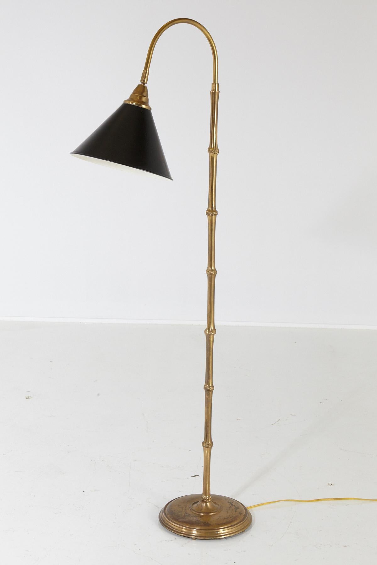 Faux bamboo brass floor lamp with swiveling black metal shade. 
The brass is of heavy, excellent quality, a solid construction.
Some tarnish to base, from age and consistent use, please refer to the photos.
Measurements: Base diameter 10 x height