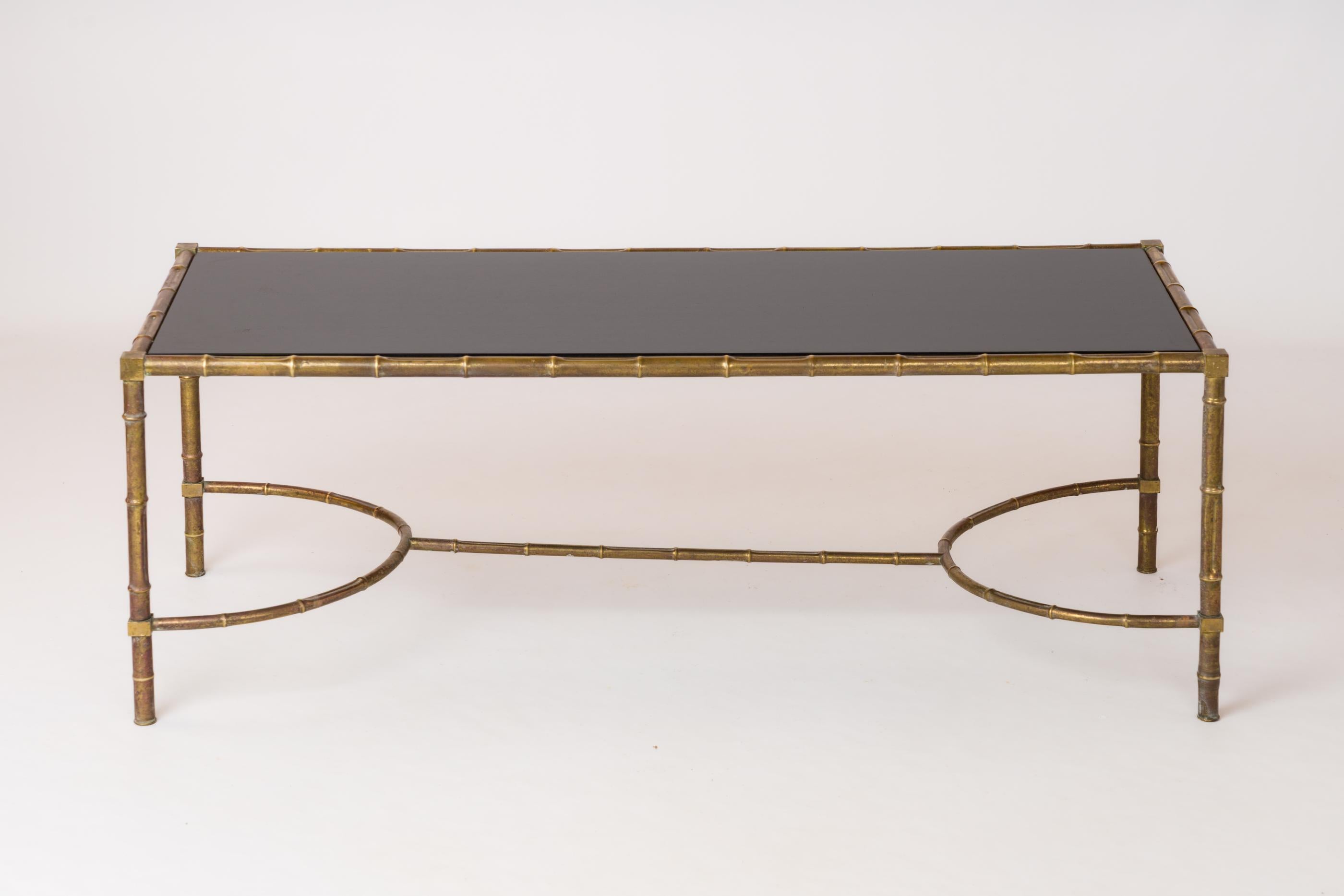 Table basse en tube de laiton avec décor en imitation de bambou. Plateau en bois laqué noir avec entretoise en double U.
En bon état vintage. Patine sur toutes les surfaces en laiton. Le plateau en bois est neuf.
Cette table est expédiée depuis la