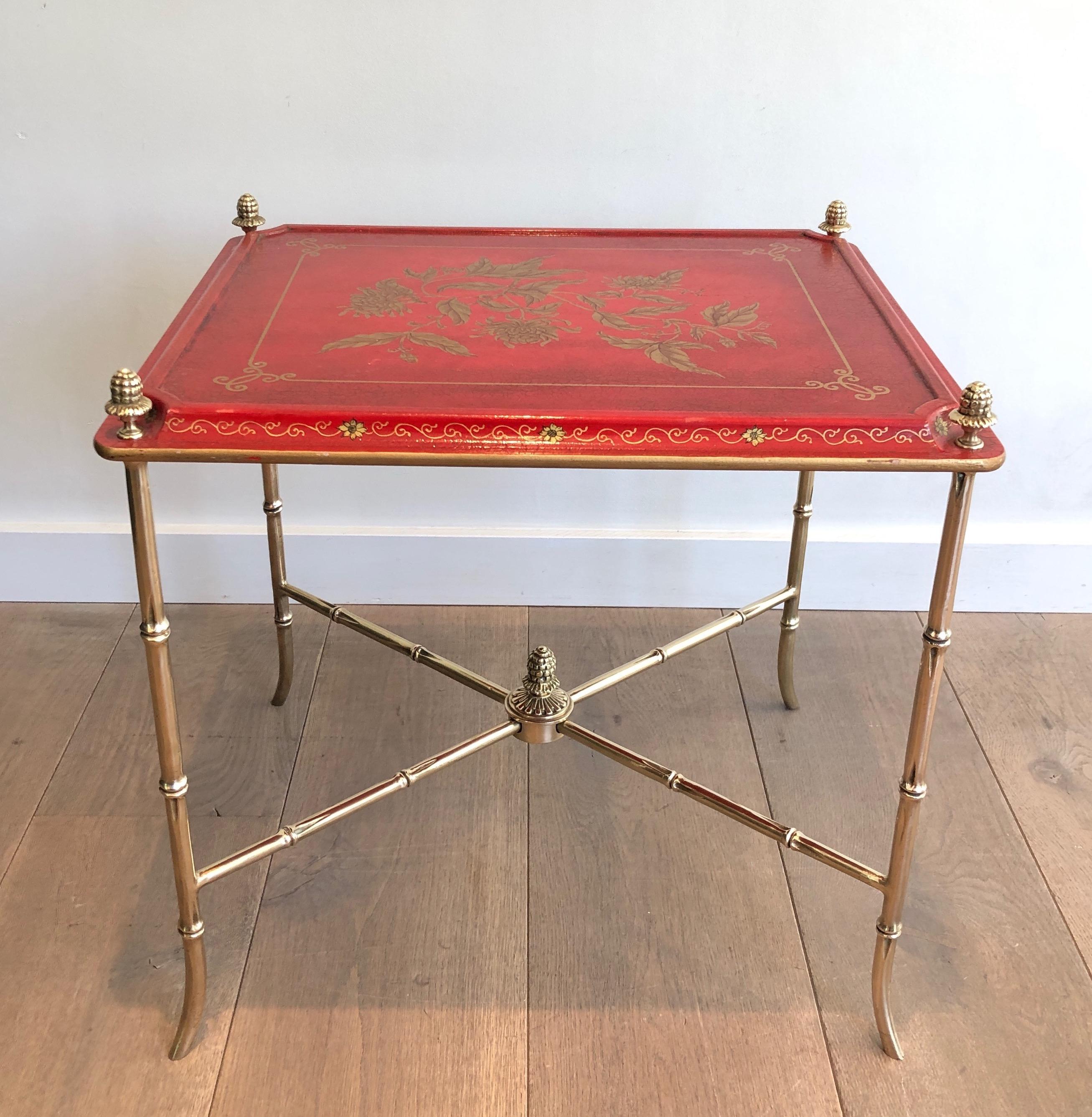 This absolutely beautiful side table is made of a bronze and brass base with a redish lacquered and gilt decor wooden top. This is a very delicate work by famous French designer Maison Baguès. Circa 1940.
 