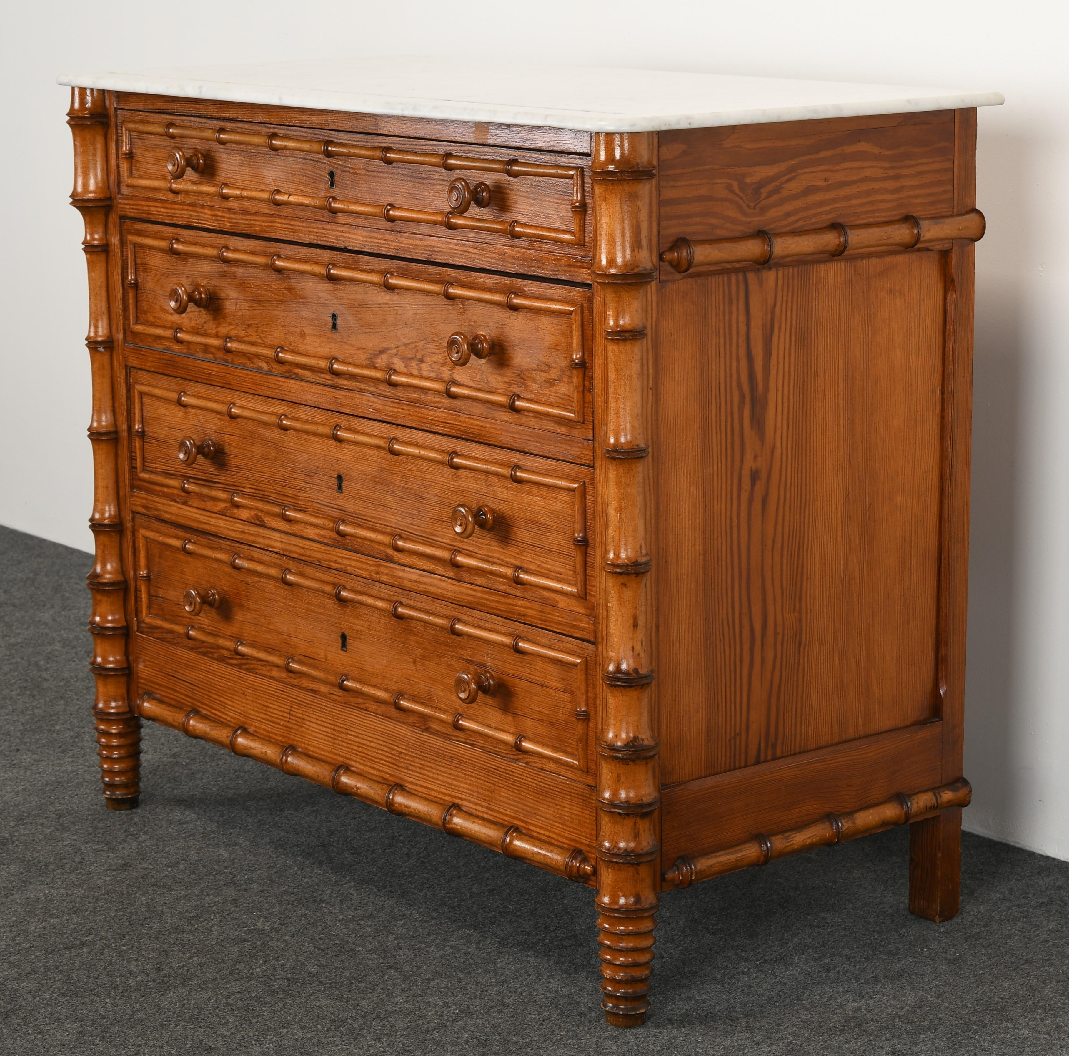 A beautiful faux bamboo pine dresser or chest of drawers with Carrera white marble top. This Victorian French or English commode could be used in any transitional or contemporary interior. The dresser has 4 drawers for ample storage. Perfect size