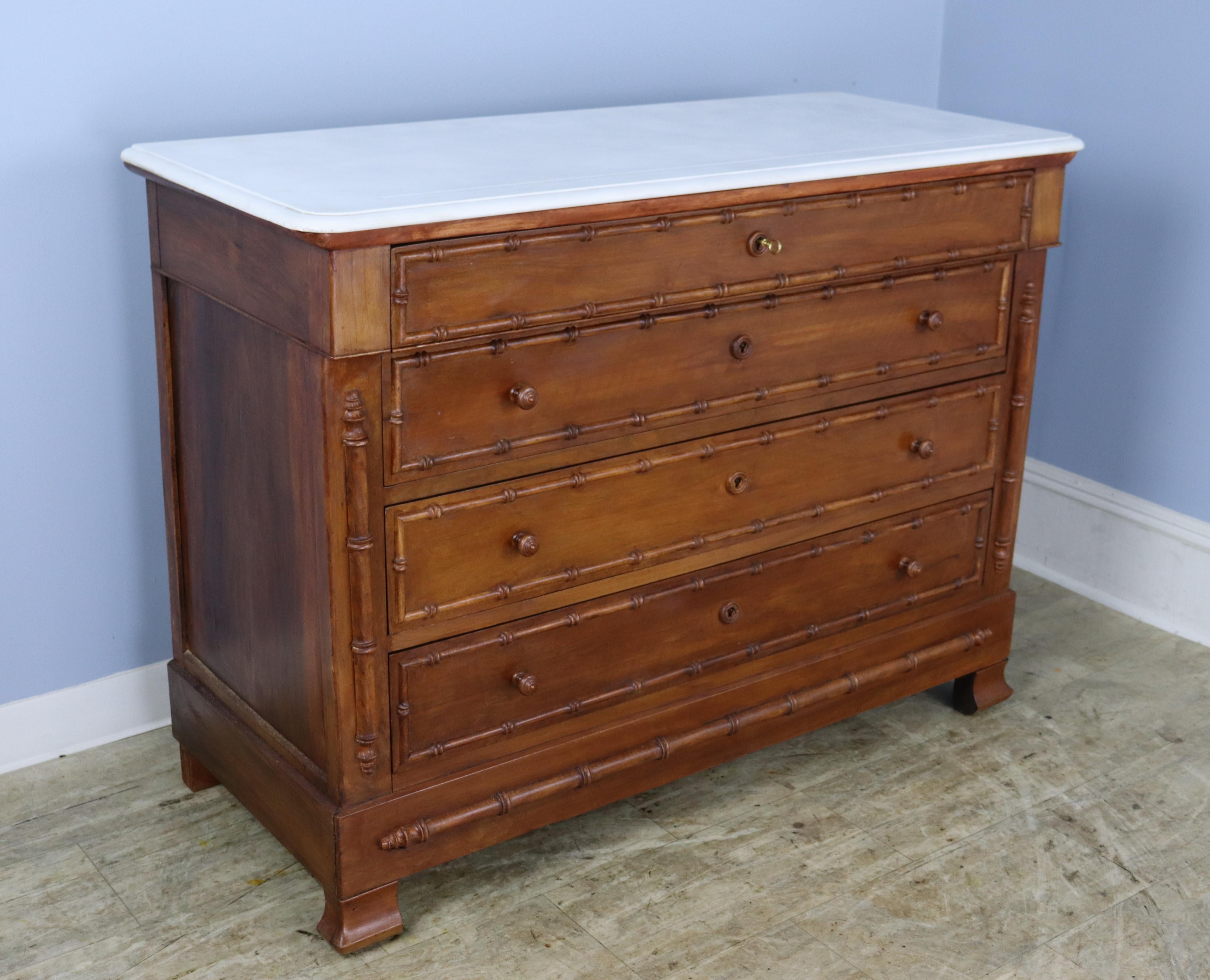 A charming chest of drawers with faux bamboo columns and mouldings. Four roomy drawers. The marble which is original is in good antique condition. 