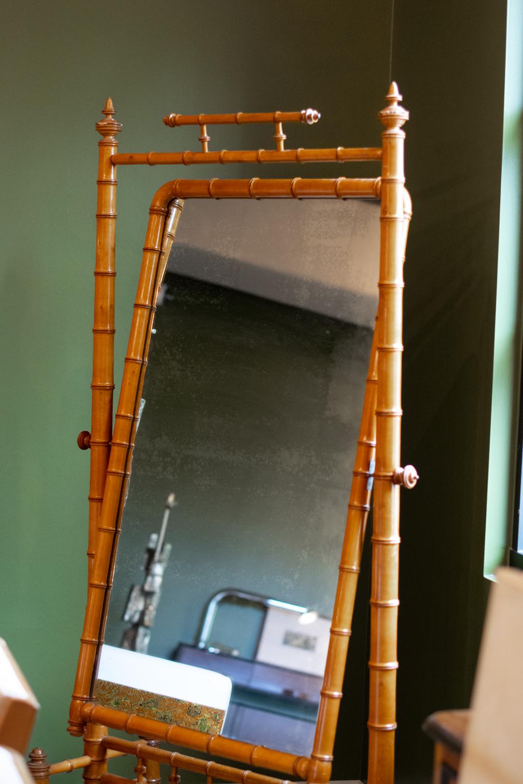 Late 19th century cheval mirror in the English tradition, but found in France, Louis Phillipe styling. Carved and stained elm replicates bamboo, framing a full length mirror that pivots in the frame. Subtle and beautiful patina to the original